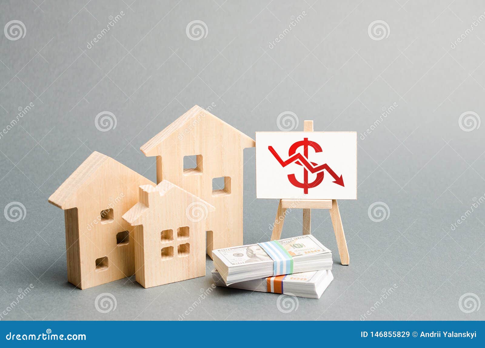 wooden figures of houses and a poster with a  of falling value. concept of real estate value decrease. low liquidity