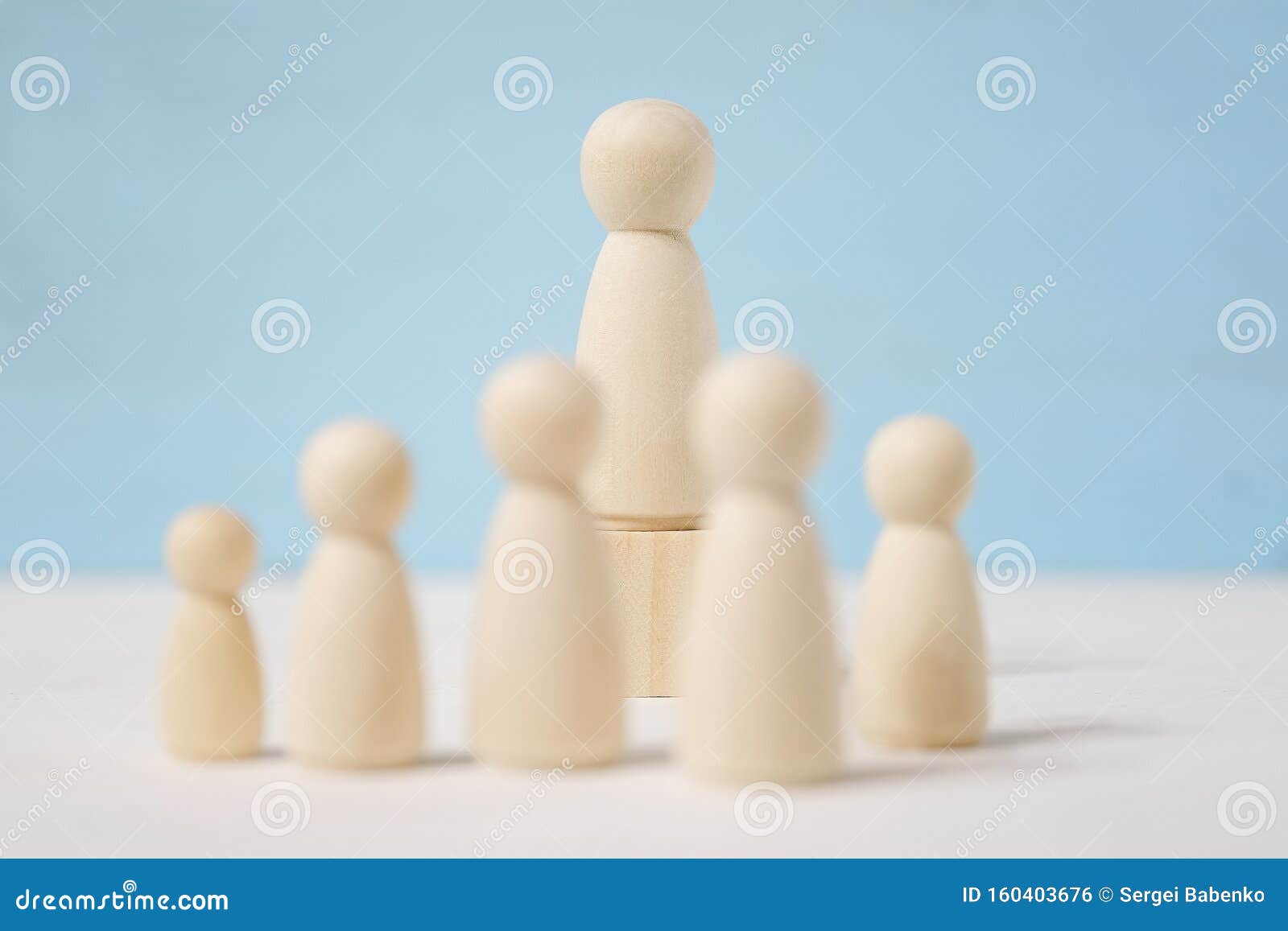wooden figures of man on toy block and people before him