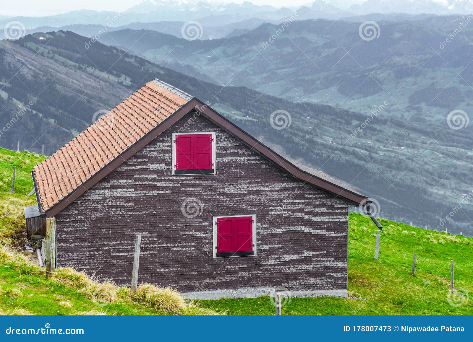 Wooden House On The Green Grass With Mountain View Background Stock