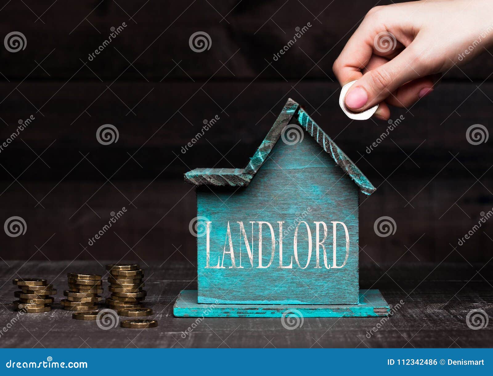 wooden house model with coins next to it and hand