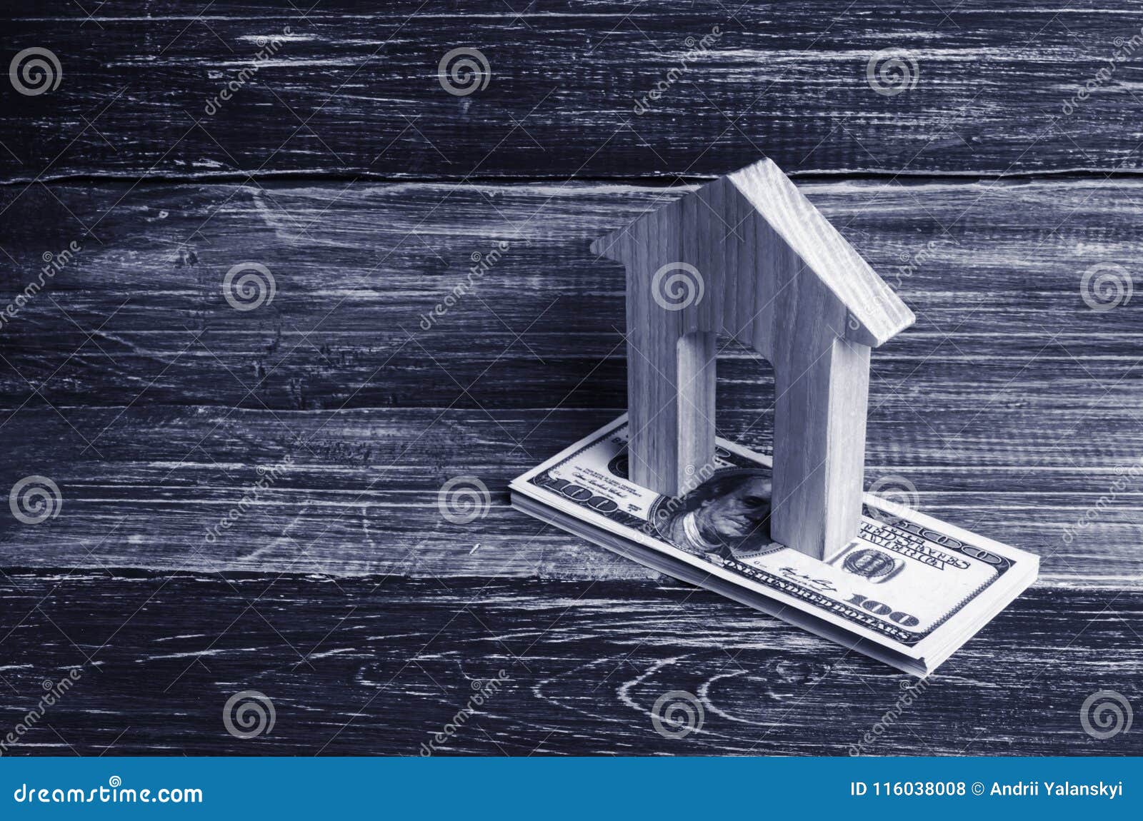 a wooden house stands on a stack of dolor banknotes.