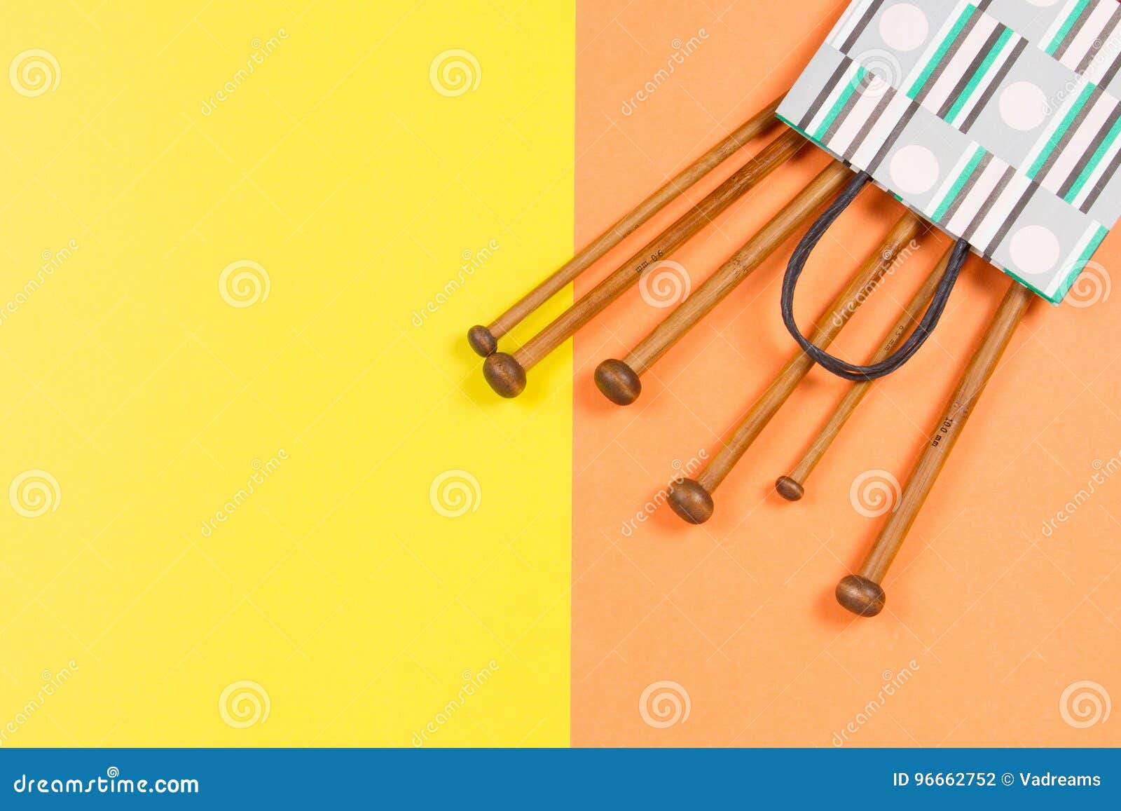 Wooden knitting needles on yellow and orange background. Top view