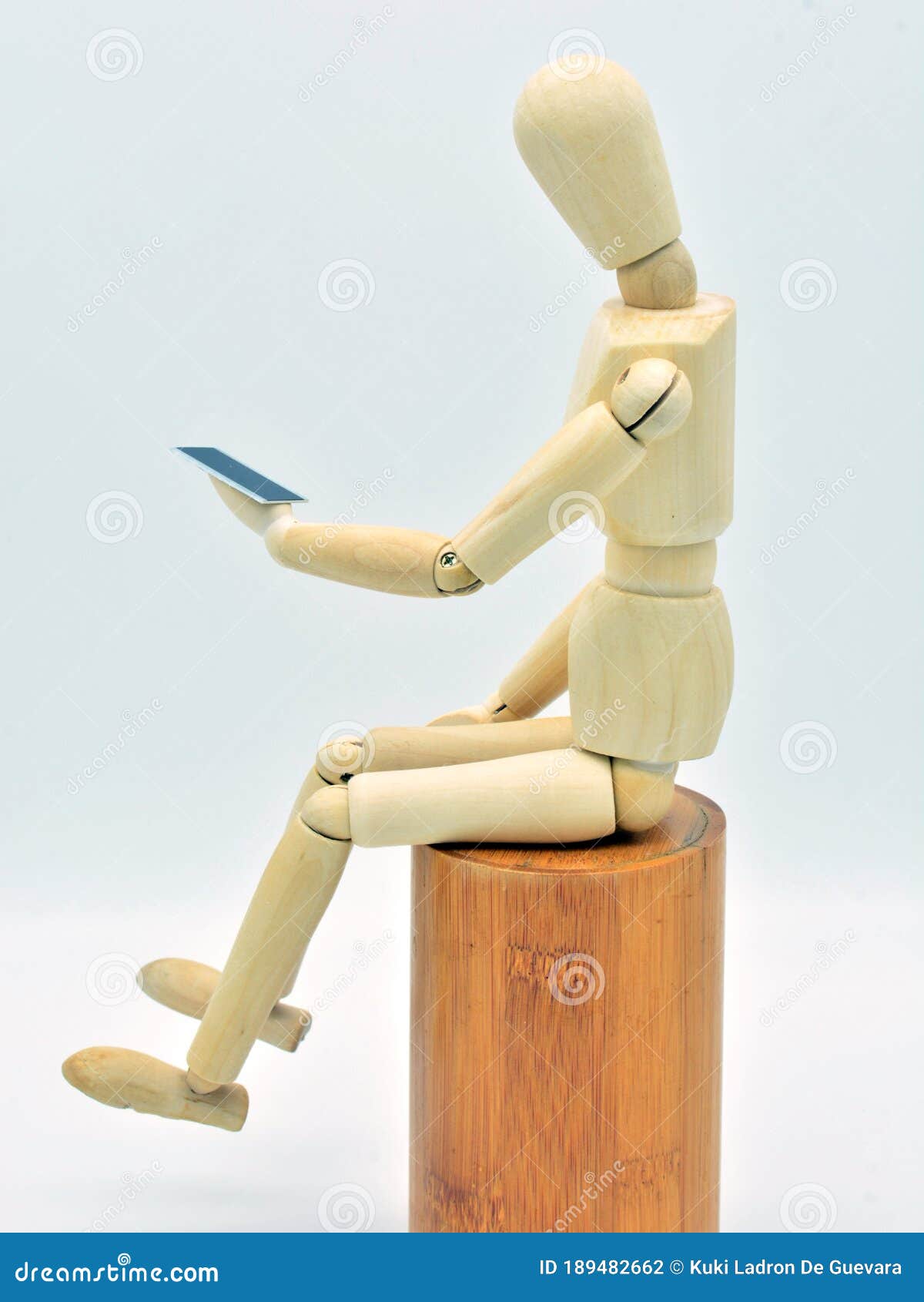 wooden mannequin with a mobile in hand