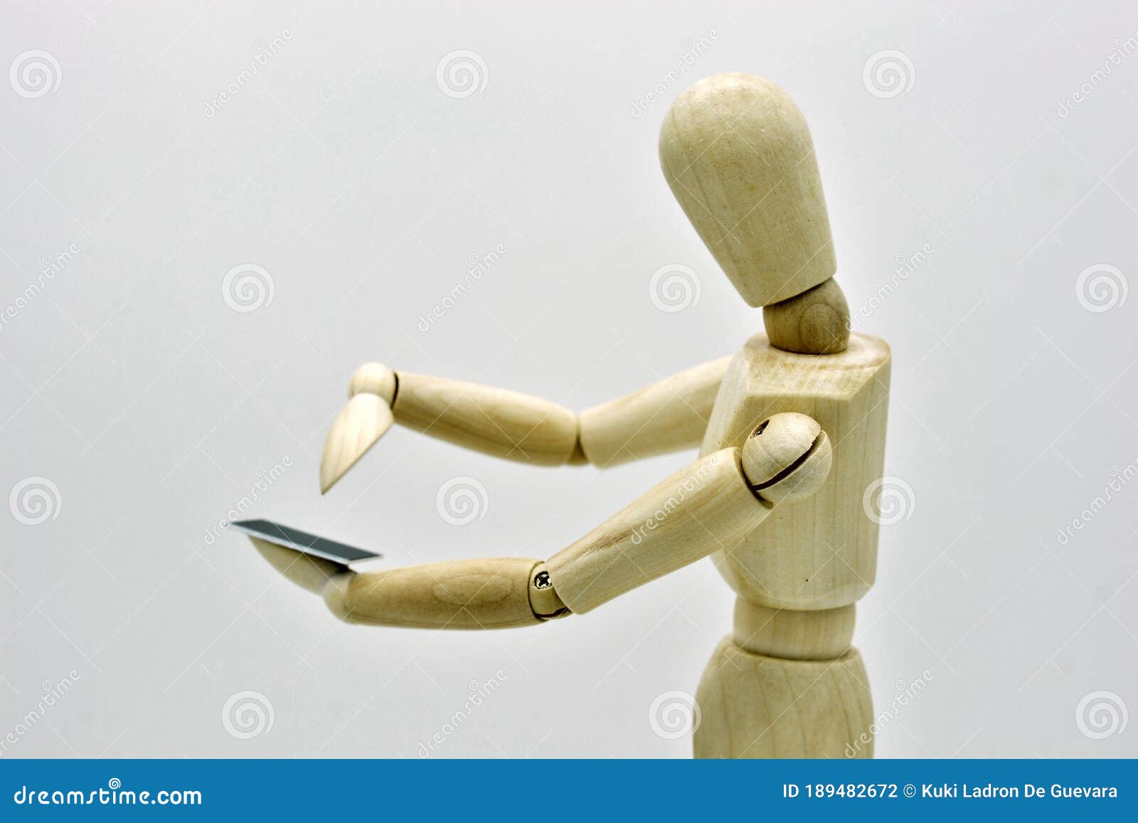 wooden mannequin with a mobile in hand
