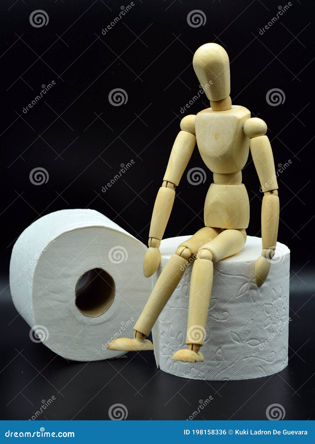 wooden mannequin sitting on a roll of toilet paper