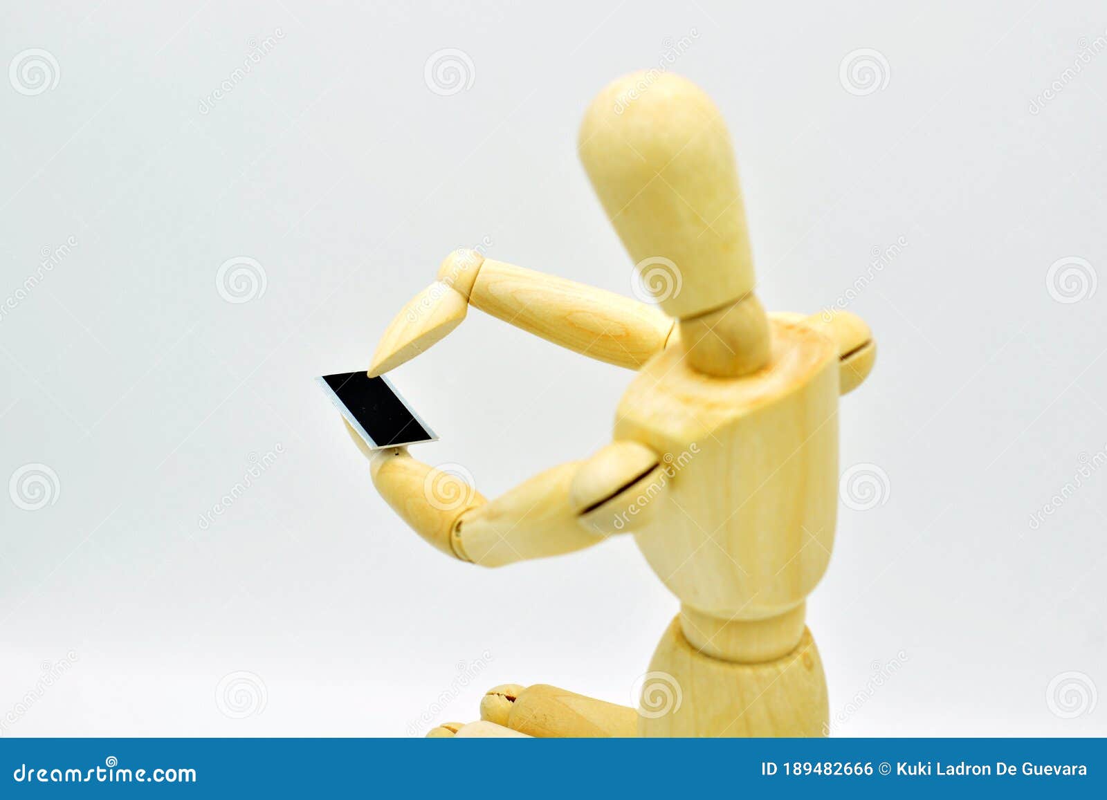 wooden mannequin with a mobile in hand