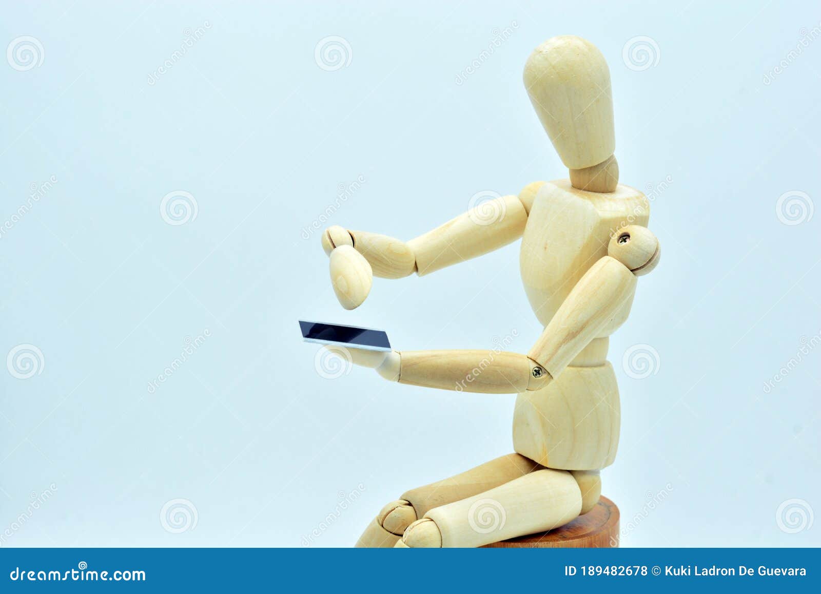 wooden mannequin with a mobile in hand