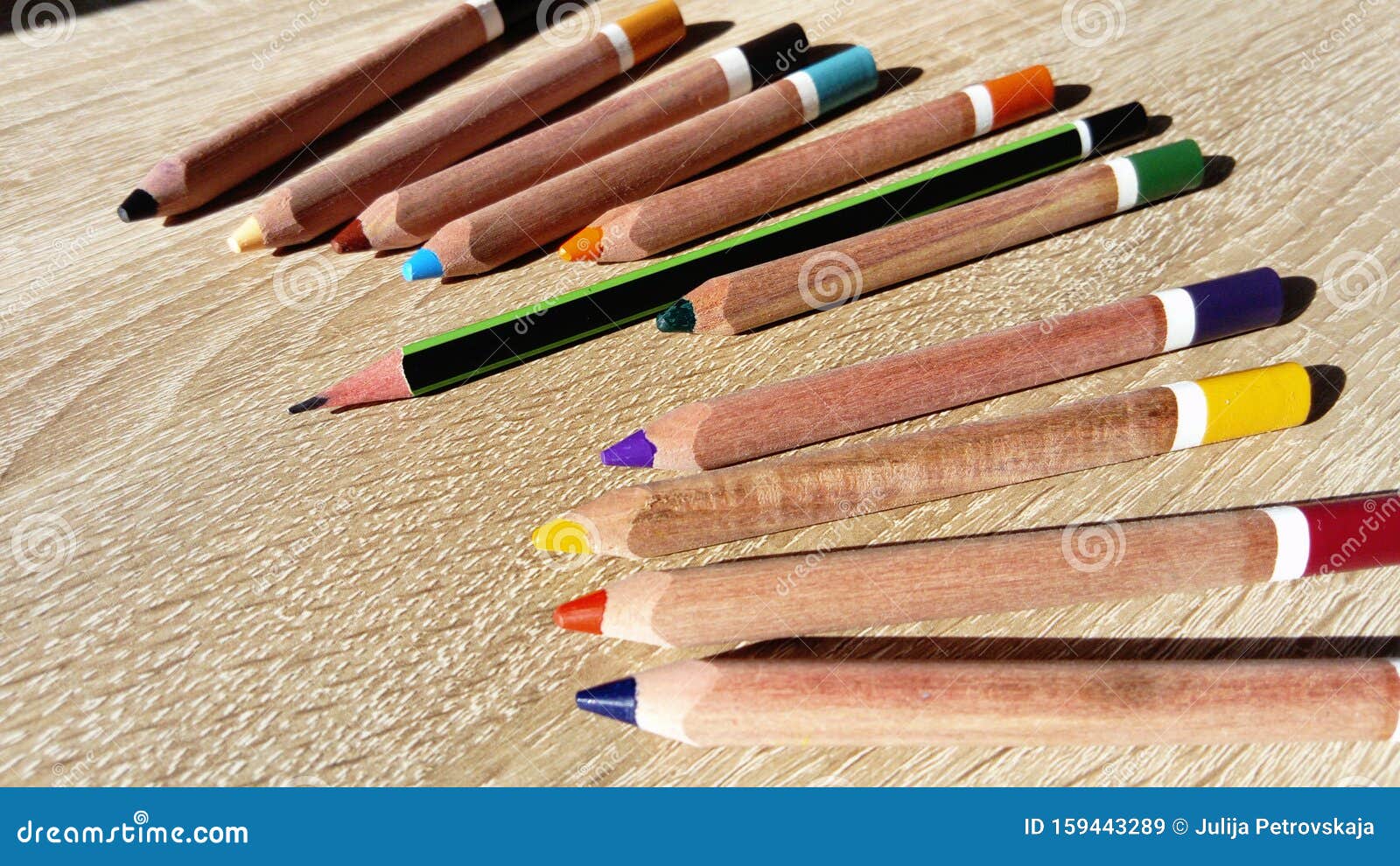 wooden pencils of different colors lie on a beige table. among them stands out one longer graphite pencil. dissimilarity,