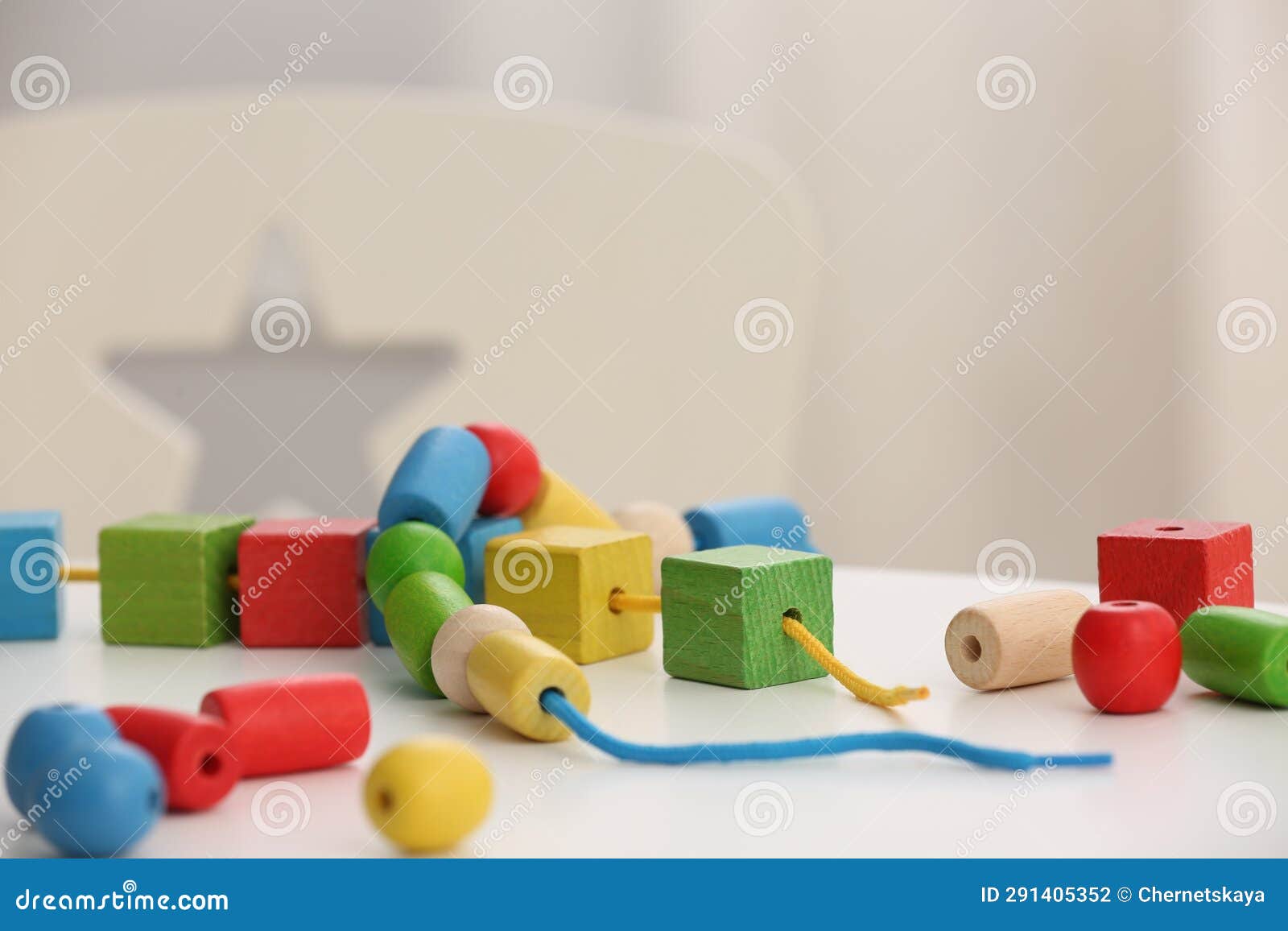 Wooden Pieces and String for Threading Activity on White Table. Motor