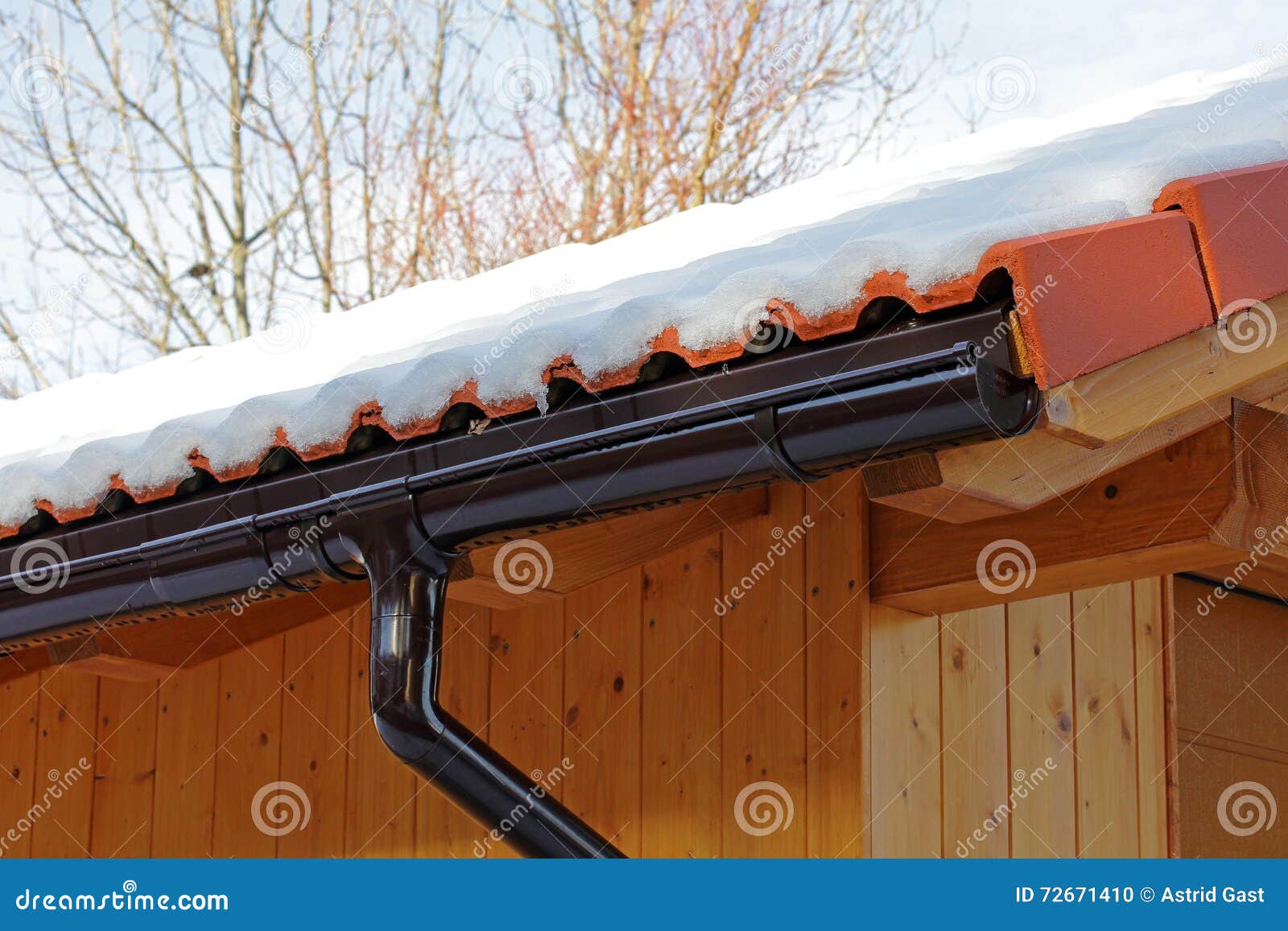 Wooden Roof with Rain Gutter and Drainpipe in Winter Stock Photo