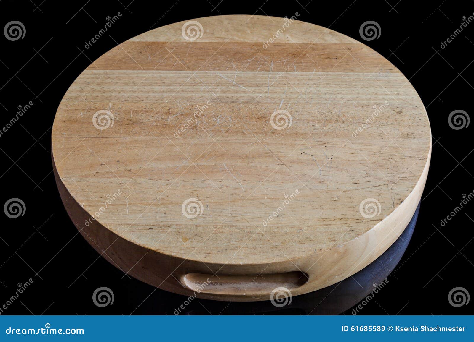 Wooden round cutting board from high angle. Bright wooden round cutting board on black surface from high angle