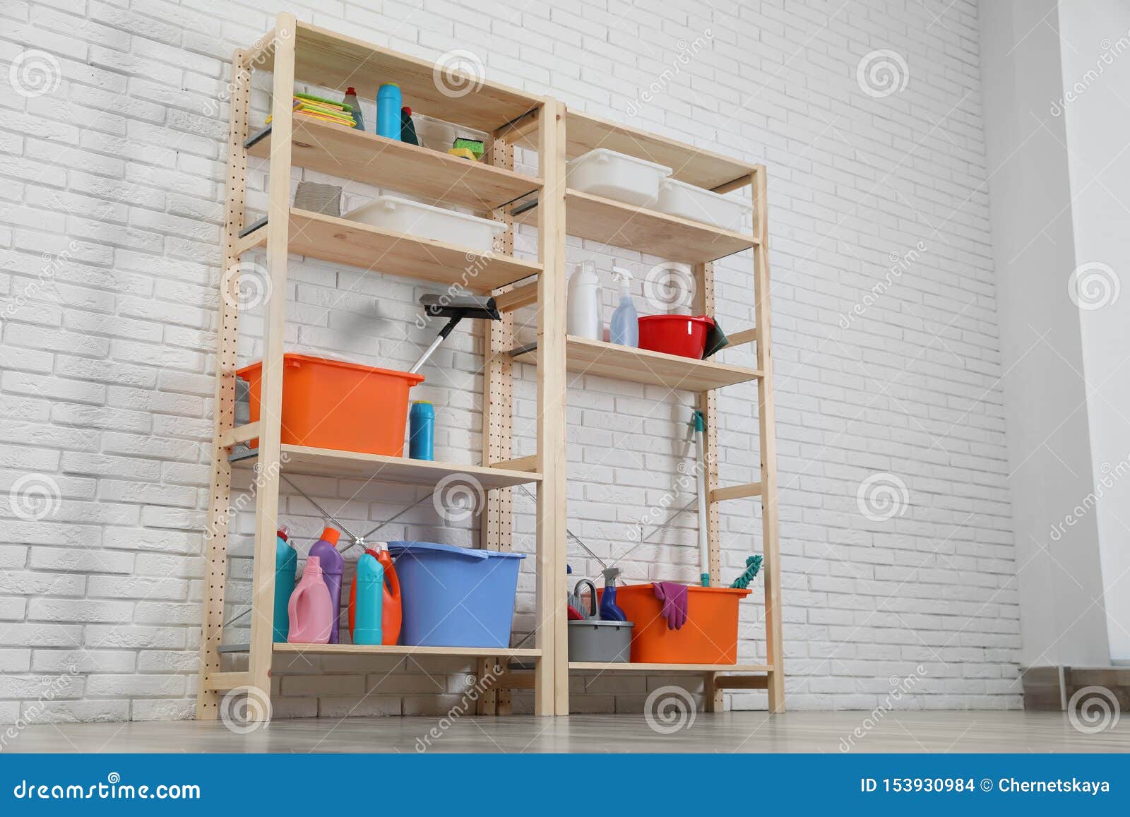 Wooden Shelving Units With Cleaning Equipment Near Brick