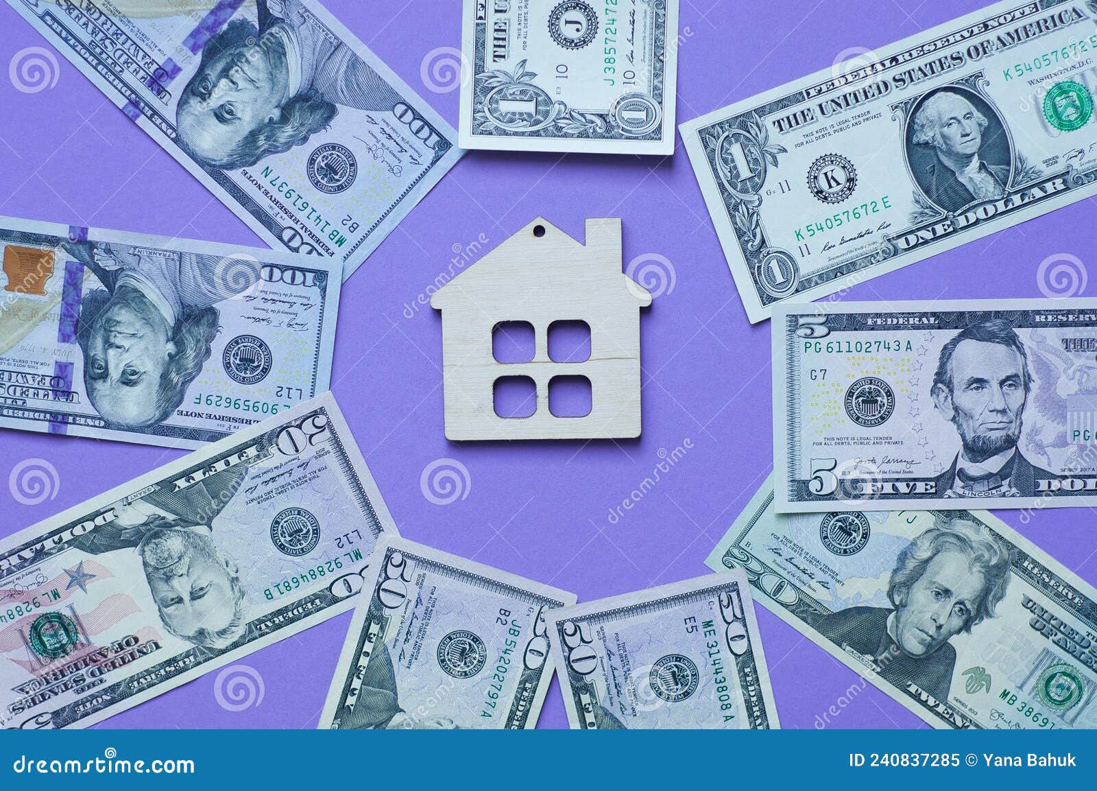 wooden small decorative house and paper money on purple background