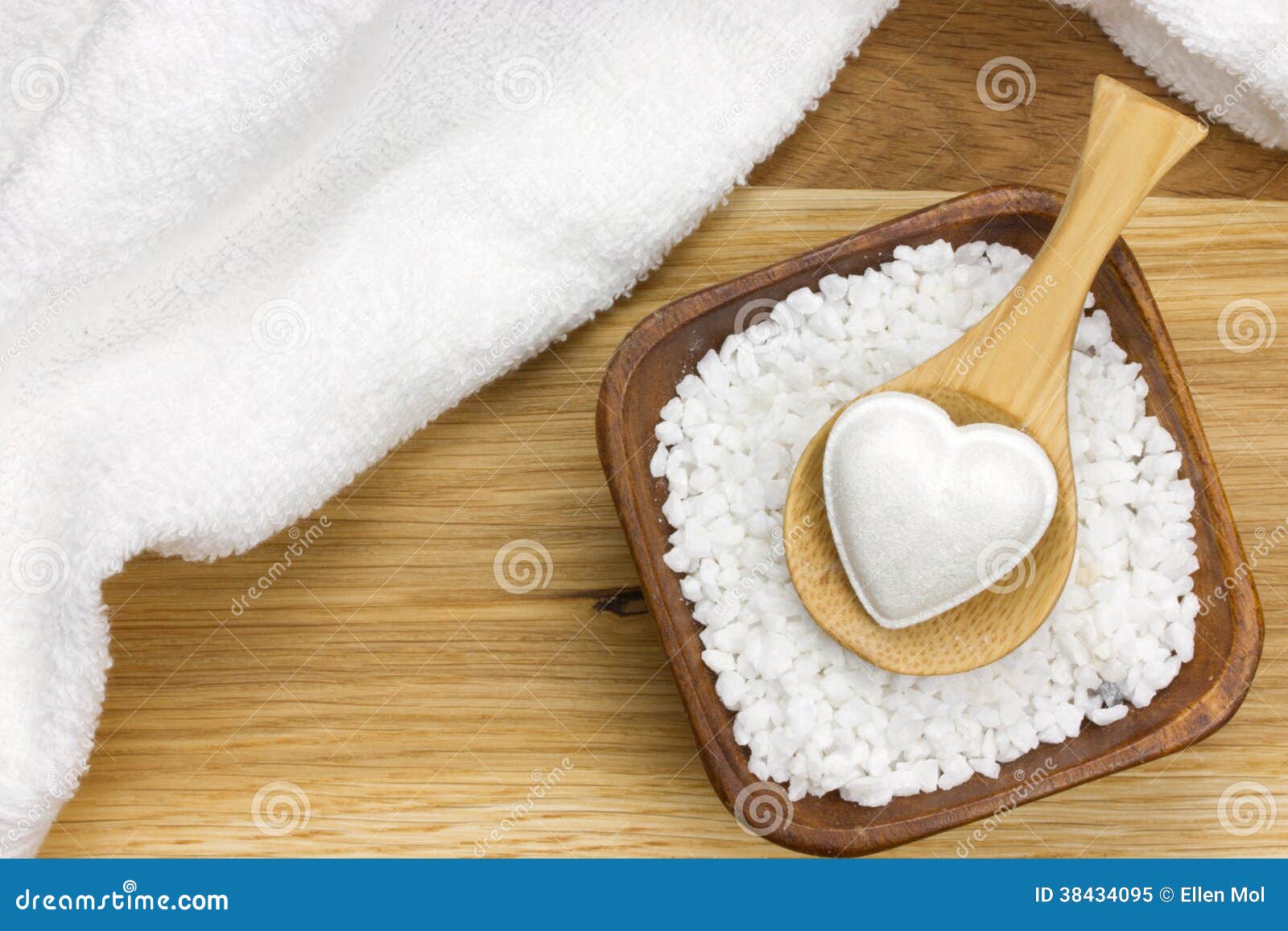 wooden spoon in bowl filled with bath salt and towel