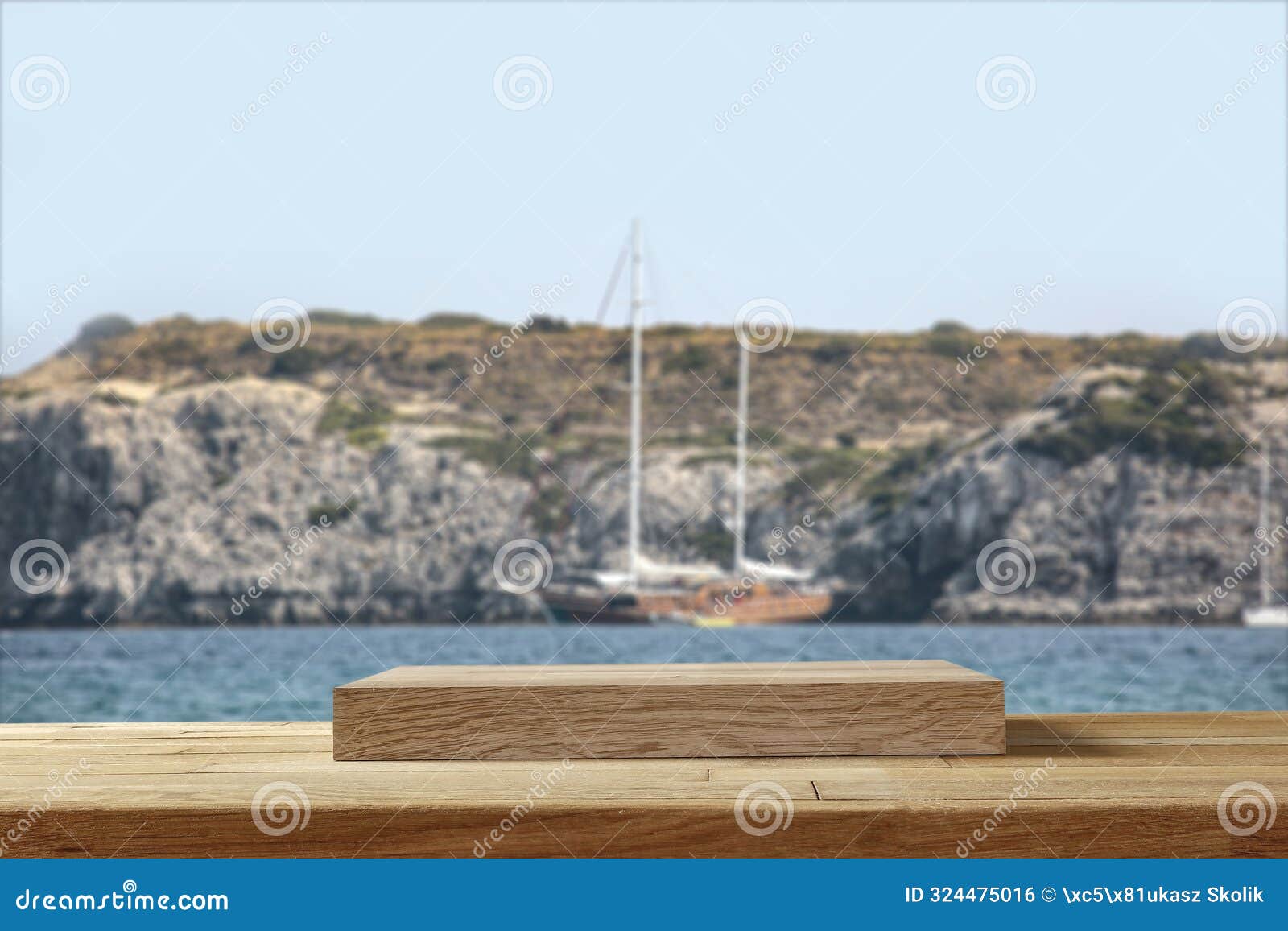 wooden summer table with blurrd boat on a stone wall. sea, rocky mountain and seascape background