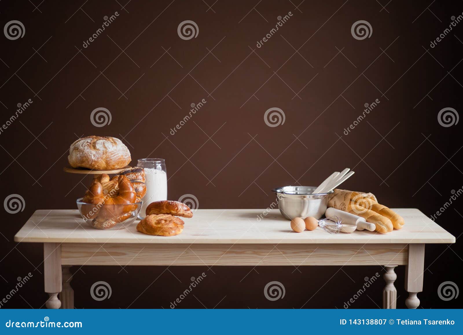 wooden table on a brown background with baked goods, bread, buns