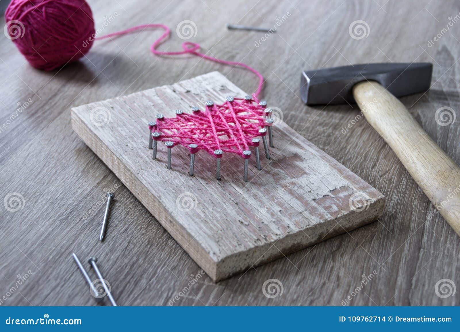 On a Wooden Table Lies a Hammer of a Nail of a Thread Pink and a