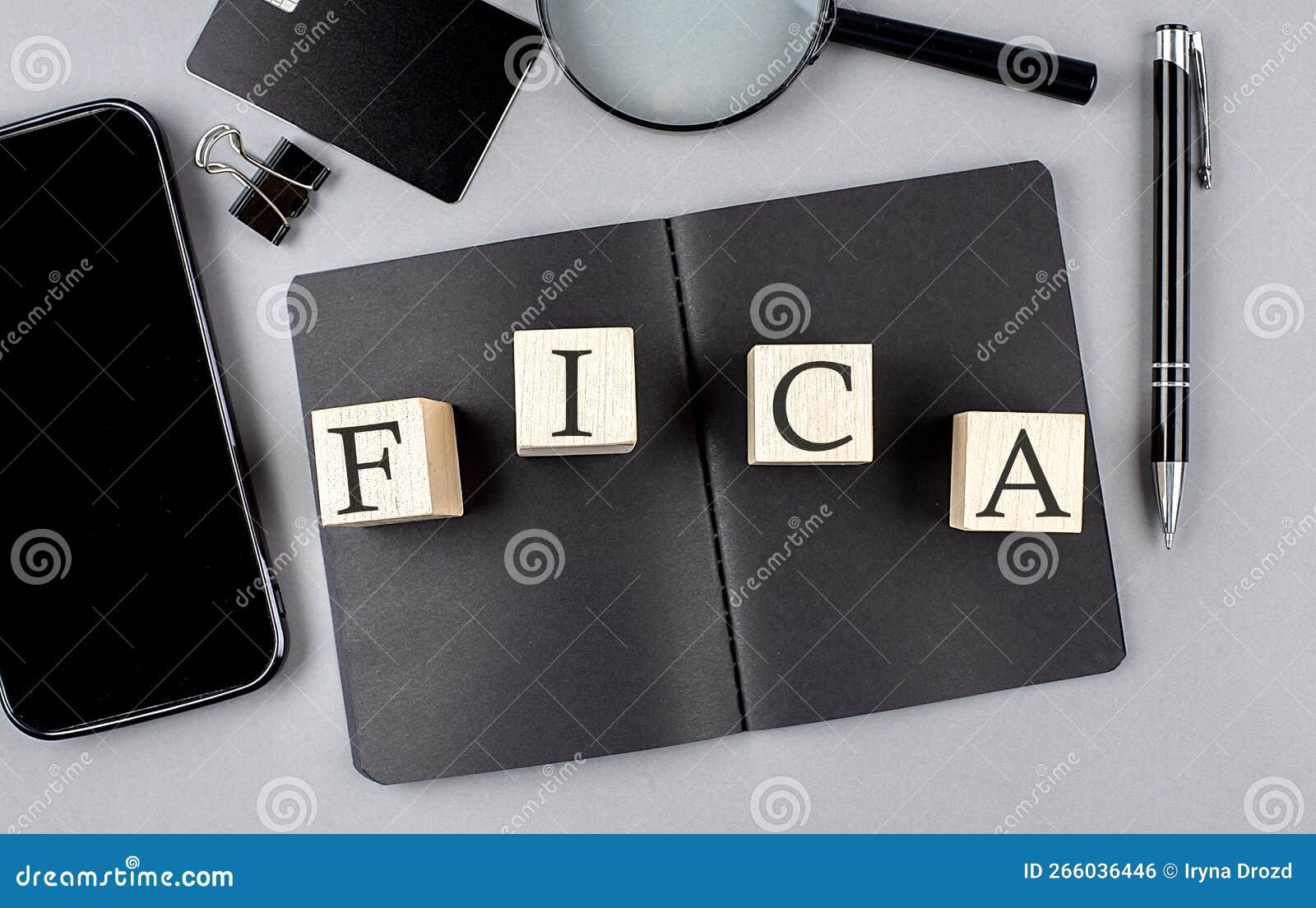 word fica on wooden block on black notebook with smartpone, credit card and magnifier