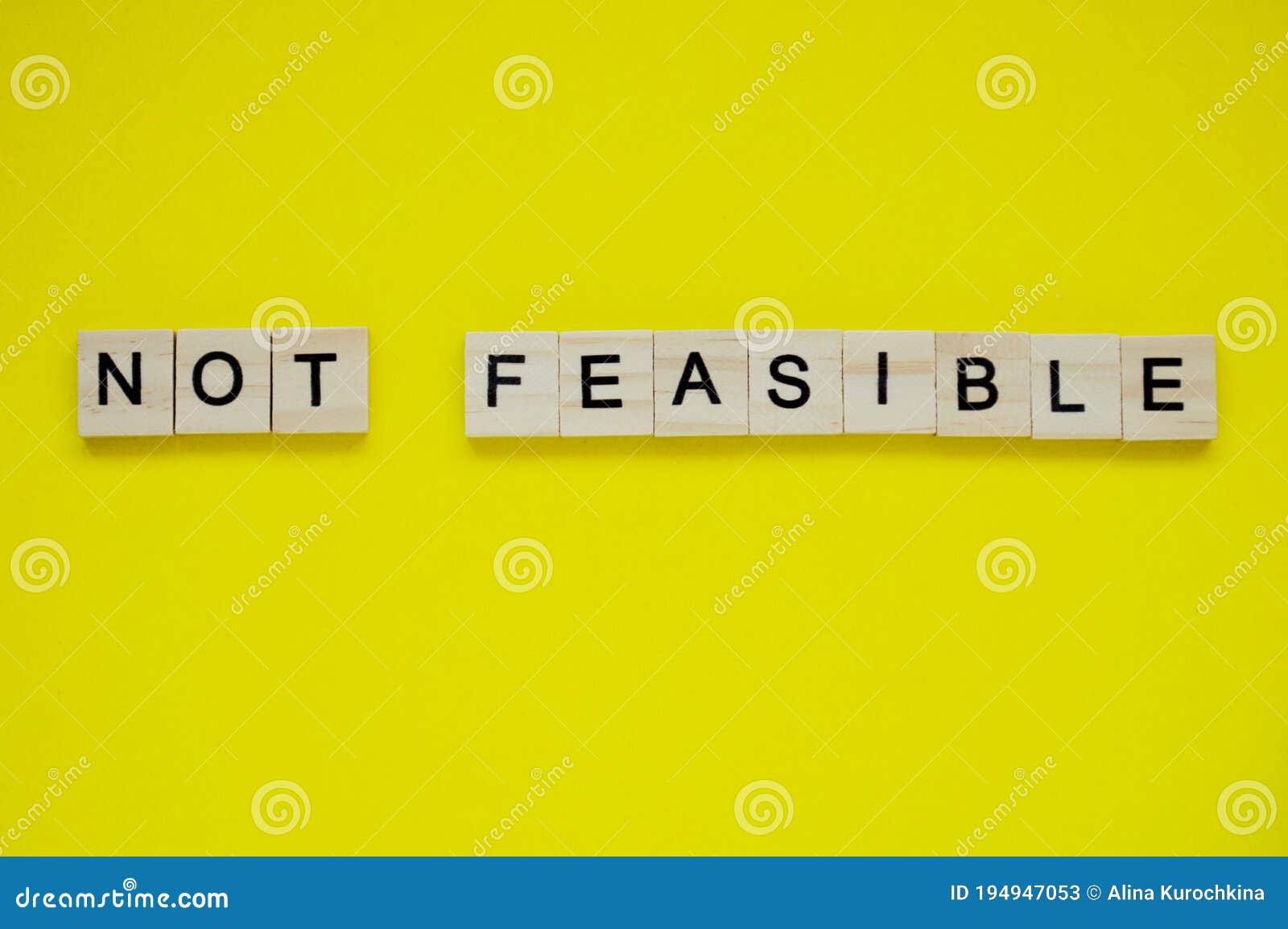word not feasible. top view of wooden blocks with letters on yellow surface