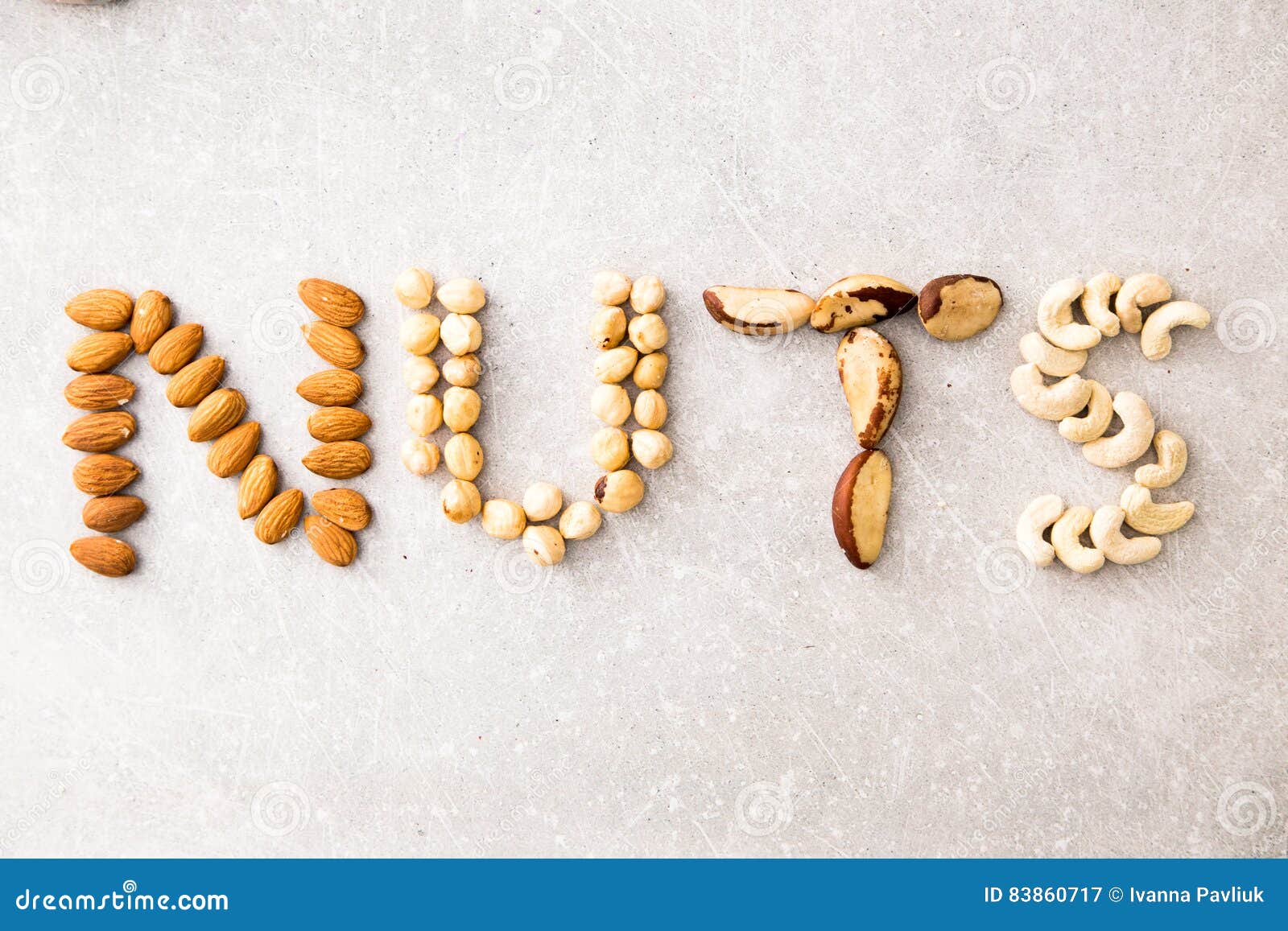 Word NUTS Spelled with Various Nuts on Stona Background. Assorted Mixed