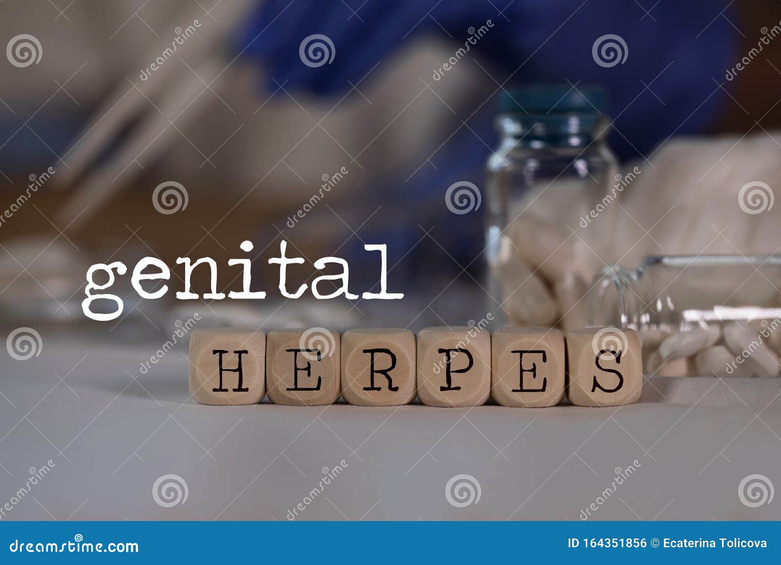words genital herpes composed of wooden dices. pills, documents and a pen in the background