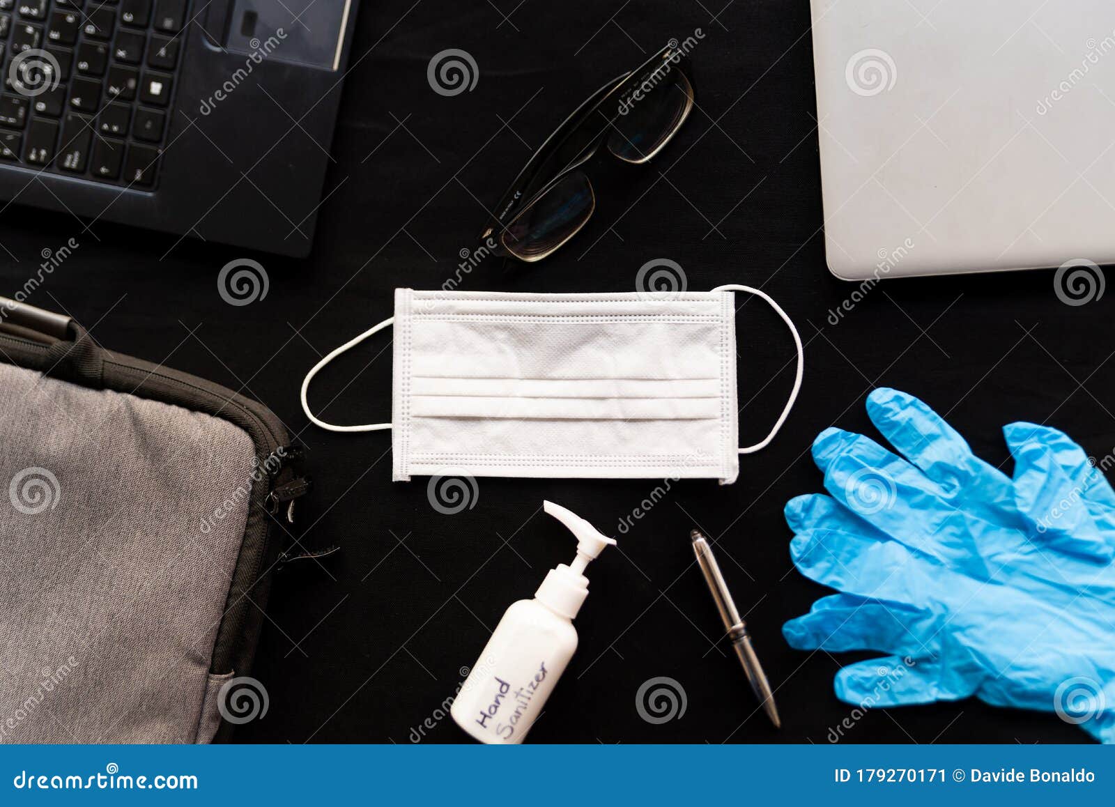 work from home cleaning kit on black background office desk with hand sanitizer and face mask and gloves, against coronavirus