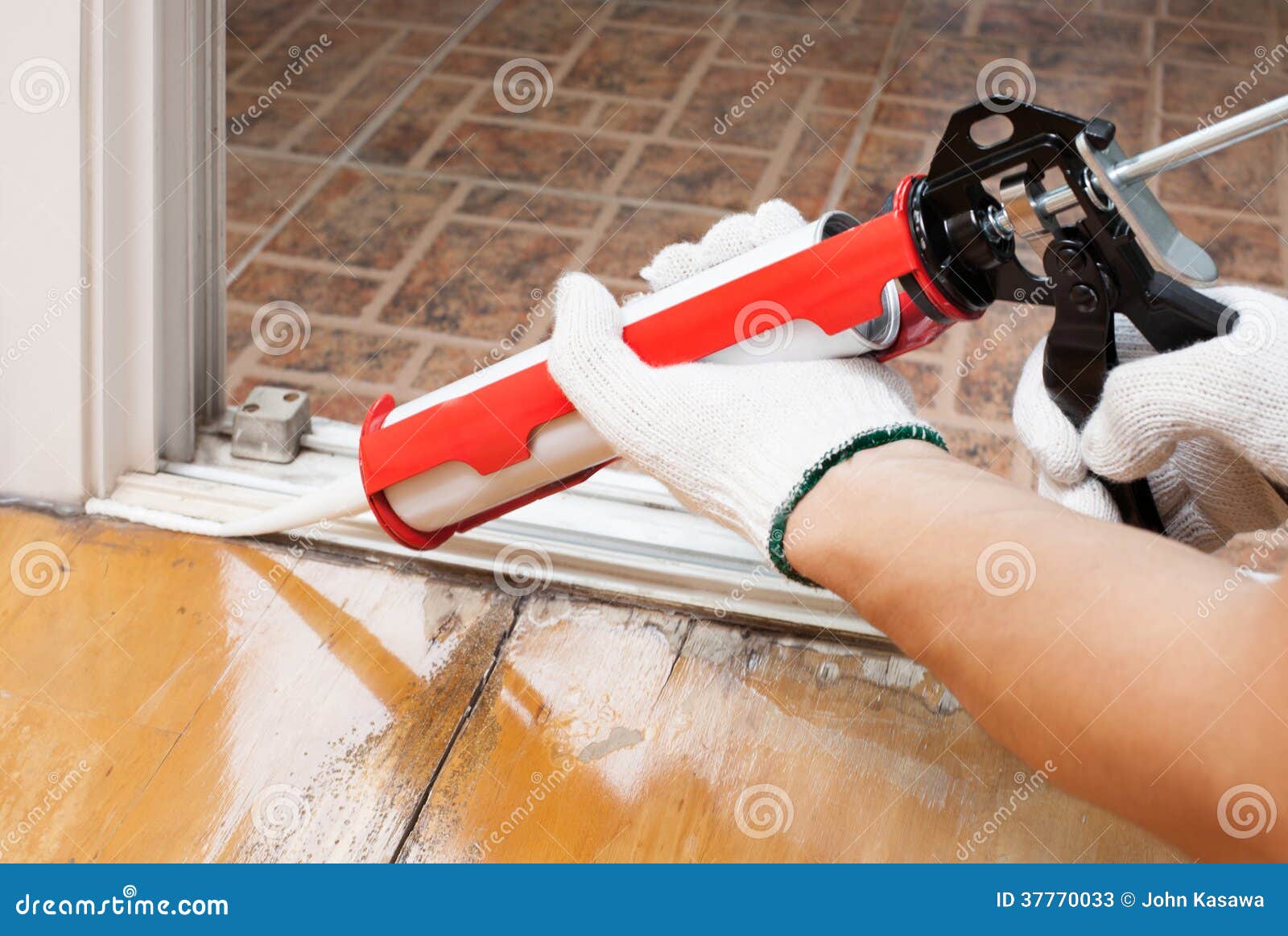 worker applies silicone caulk on the floor for sea