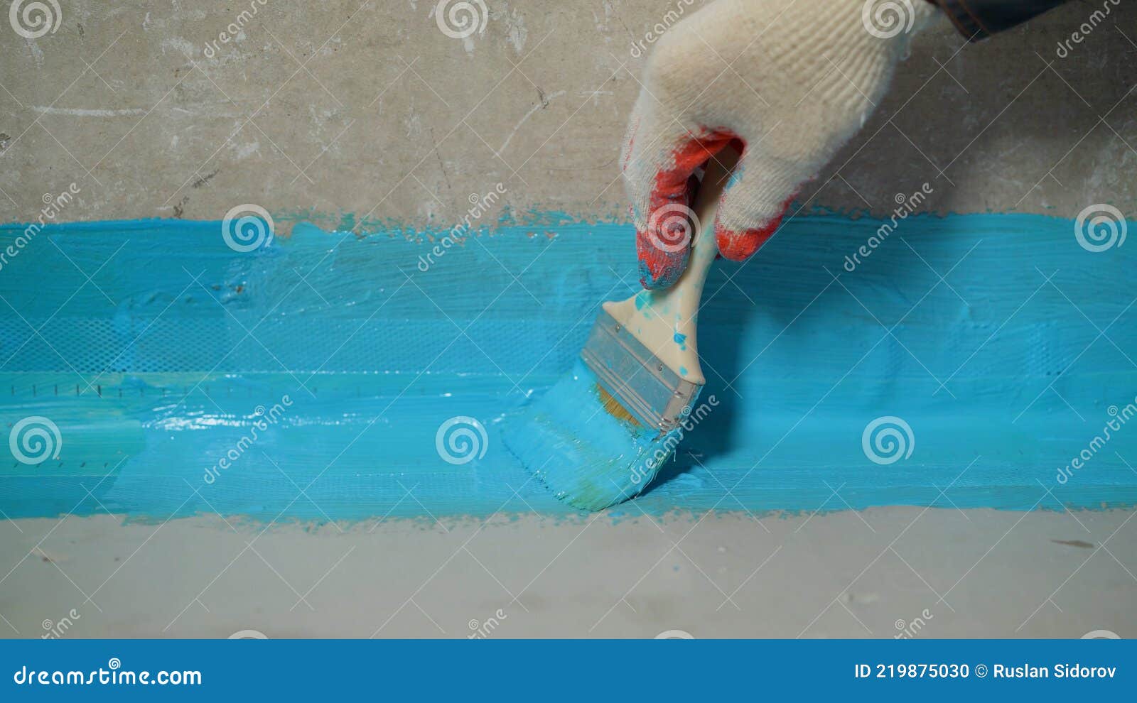 A Worker Is Applying Waterproofing Paint To The Floor In The Bathroom
