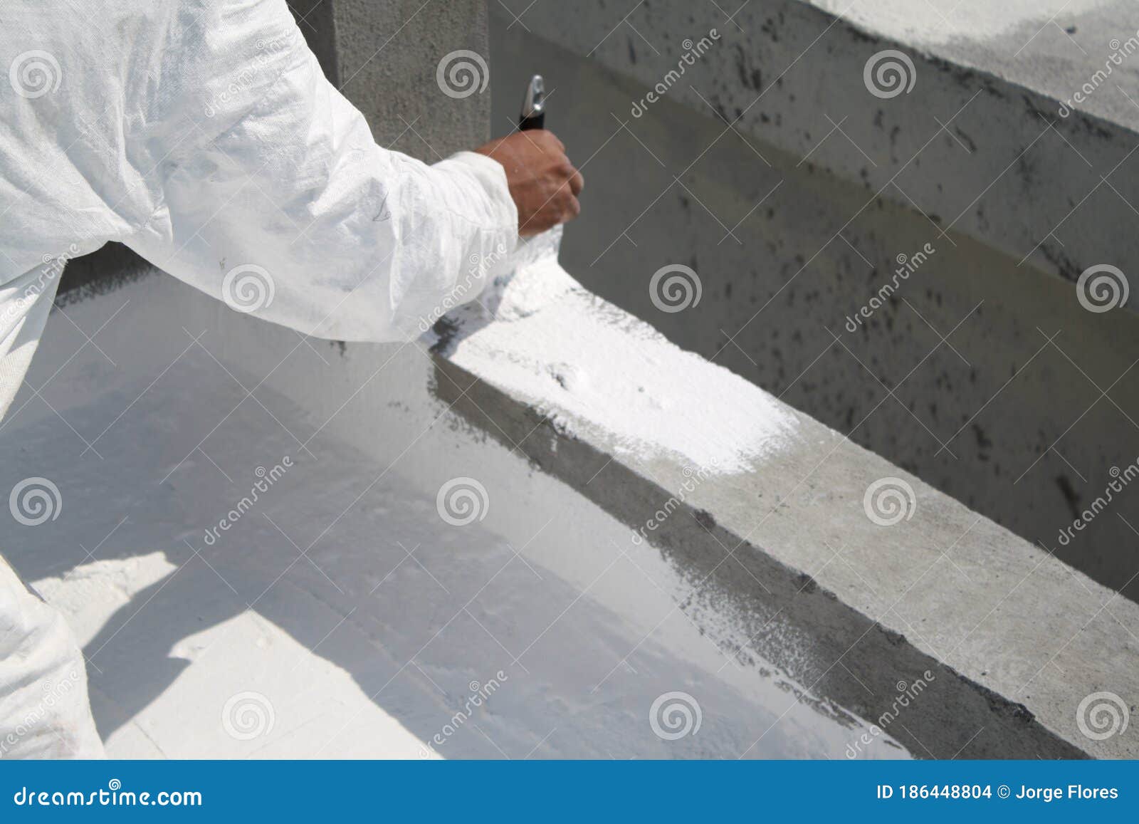 worker applying white roof coating