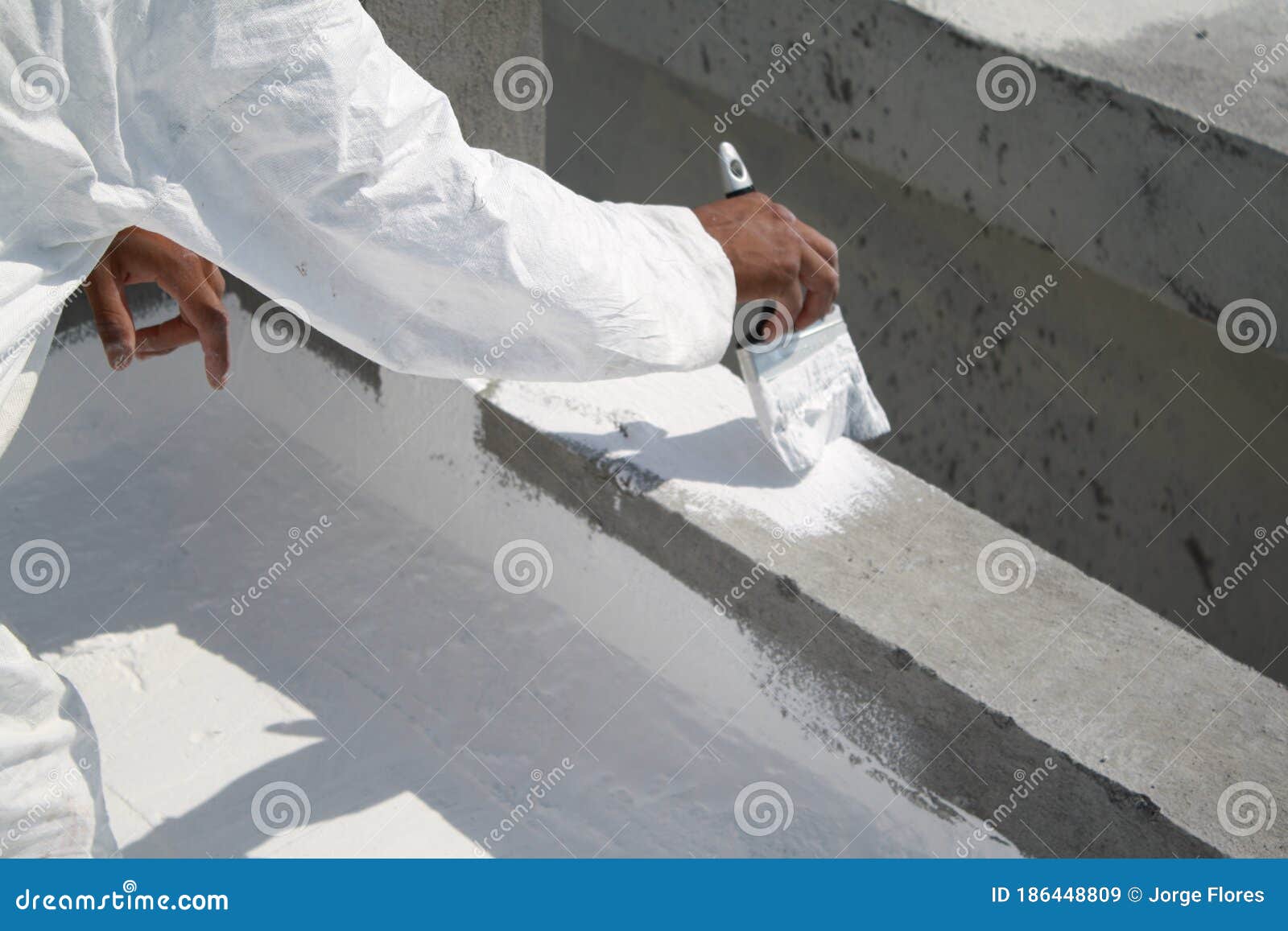 worker applying white roof coating