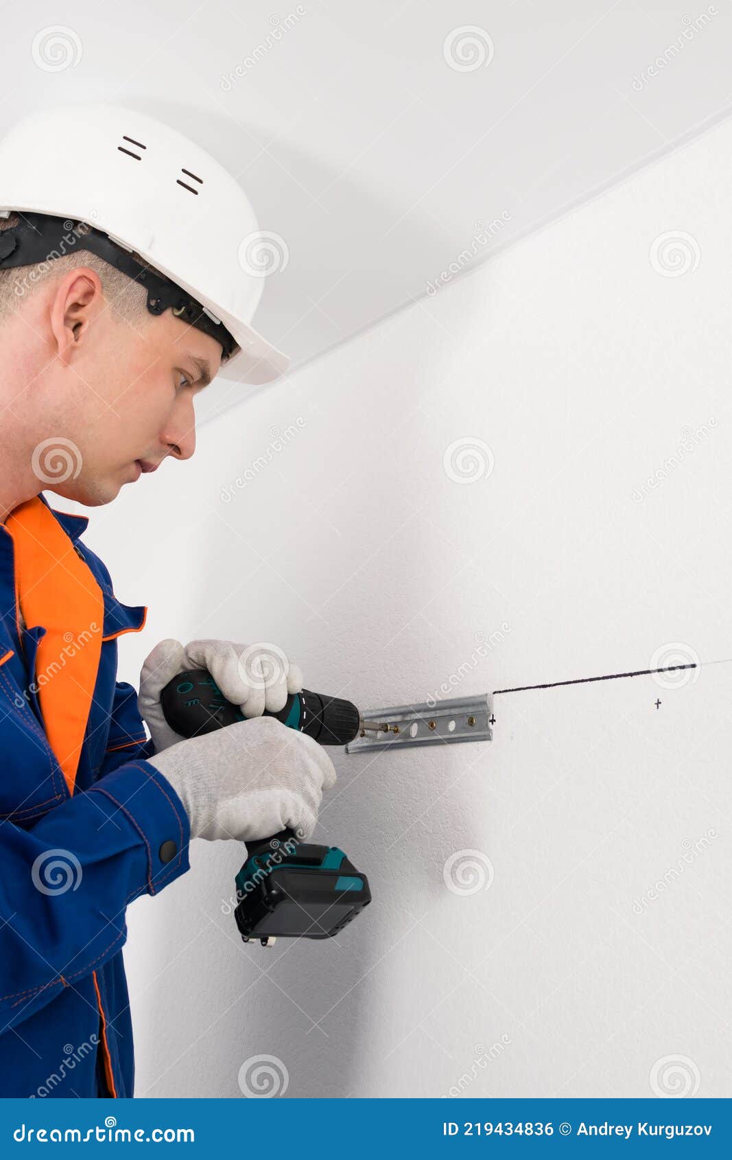 A Worker Attaches To the White Wall the Fasteners for Hanging Kitchen
