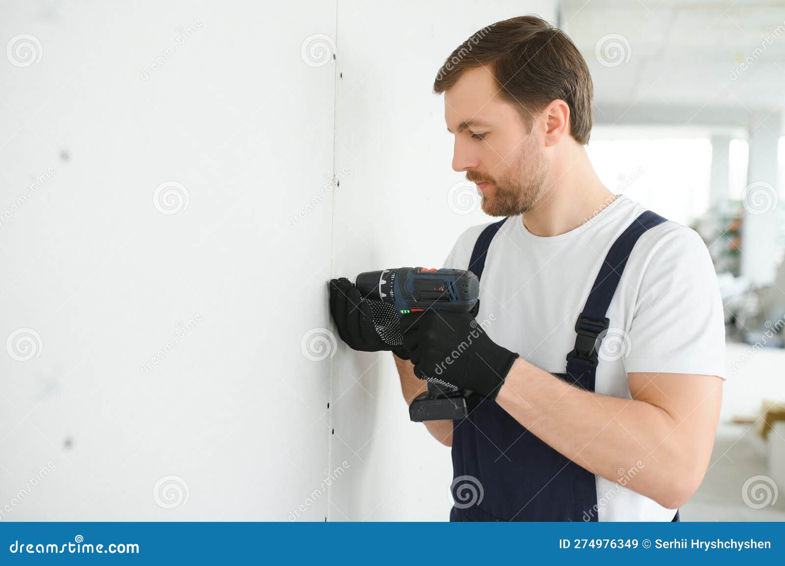 Worker Builder Installs Plasterboard Drywall at a Construction Stock