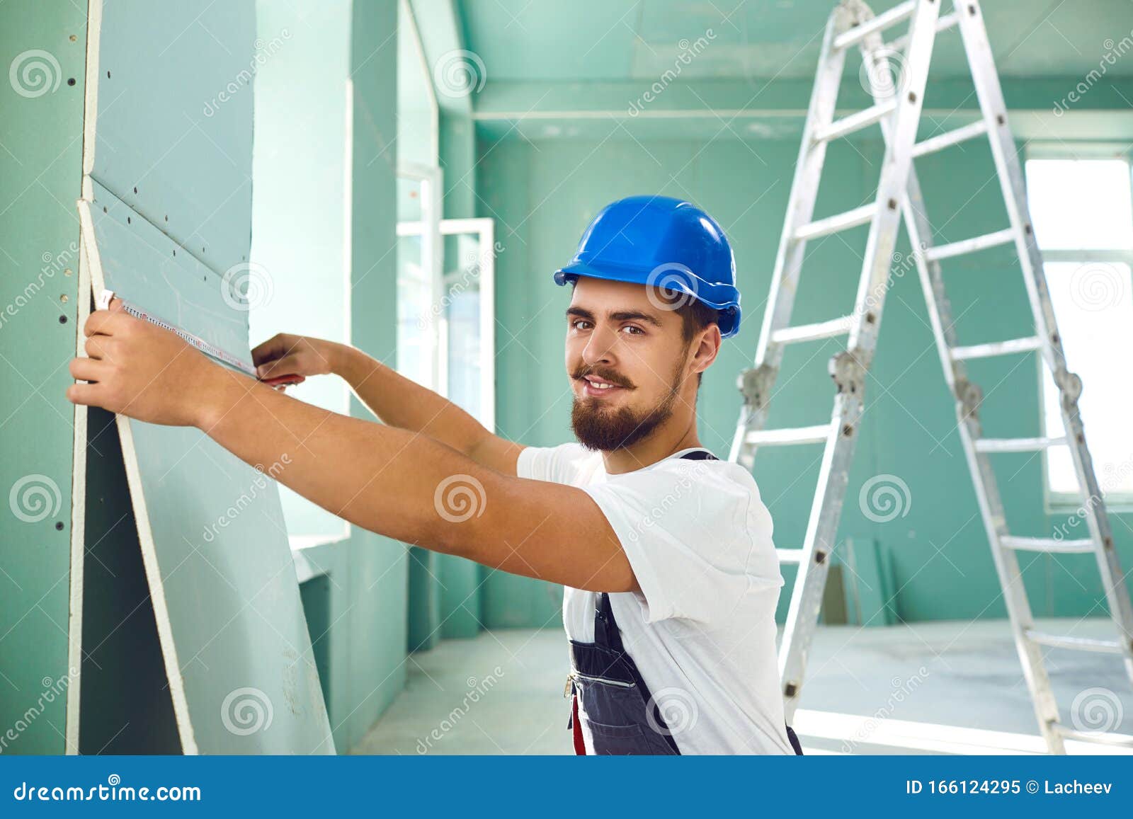 Worker Builder Installs Plasterboard Drywall at a Construction Stock