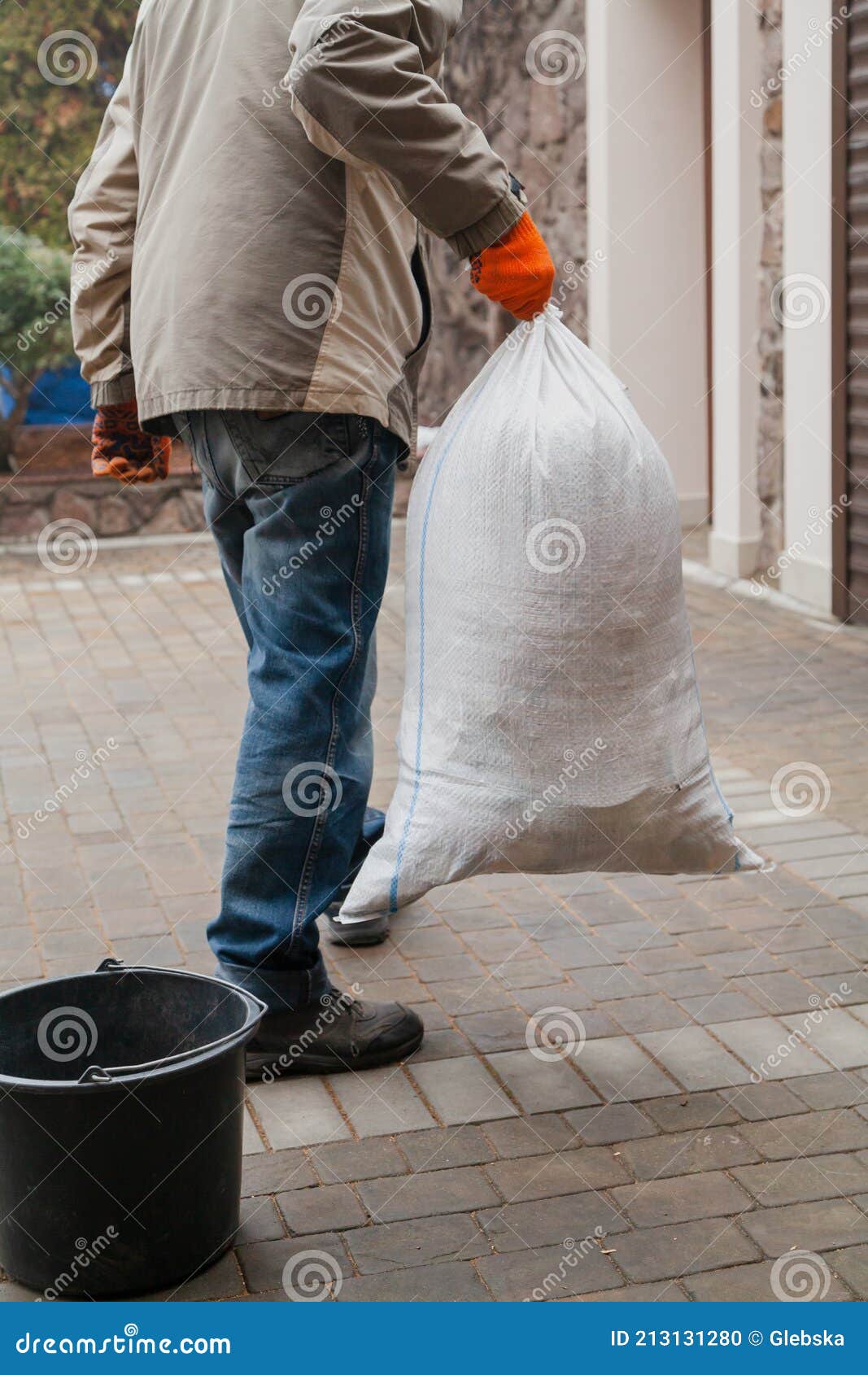 Worker Carries White Bag in Yard Stock Photo Image of sidewalk, tiles