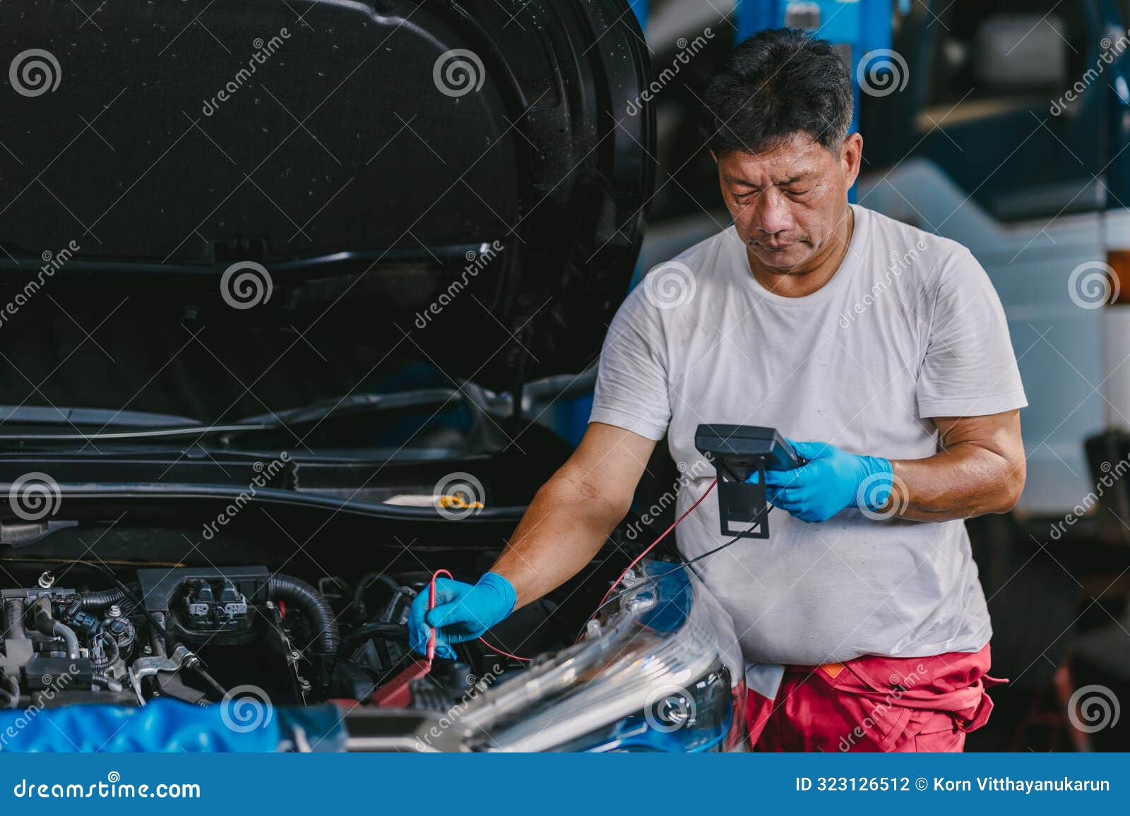 worker checking car battery voltage with multi meter, technician metering vehicle electricity at front hood