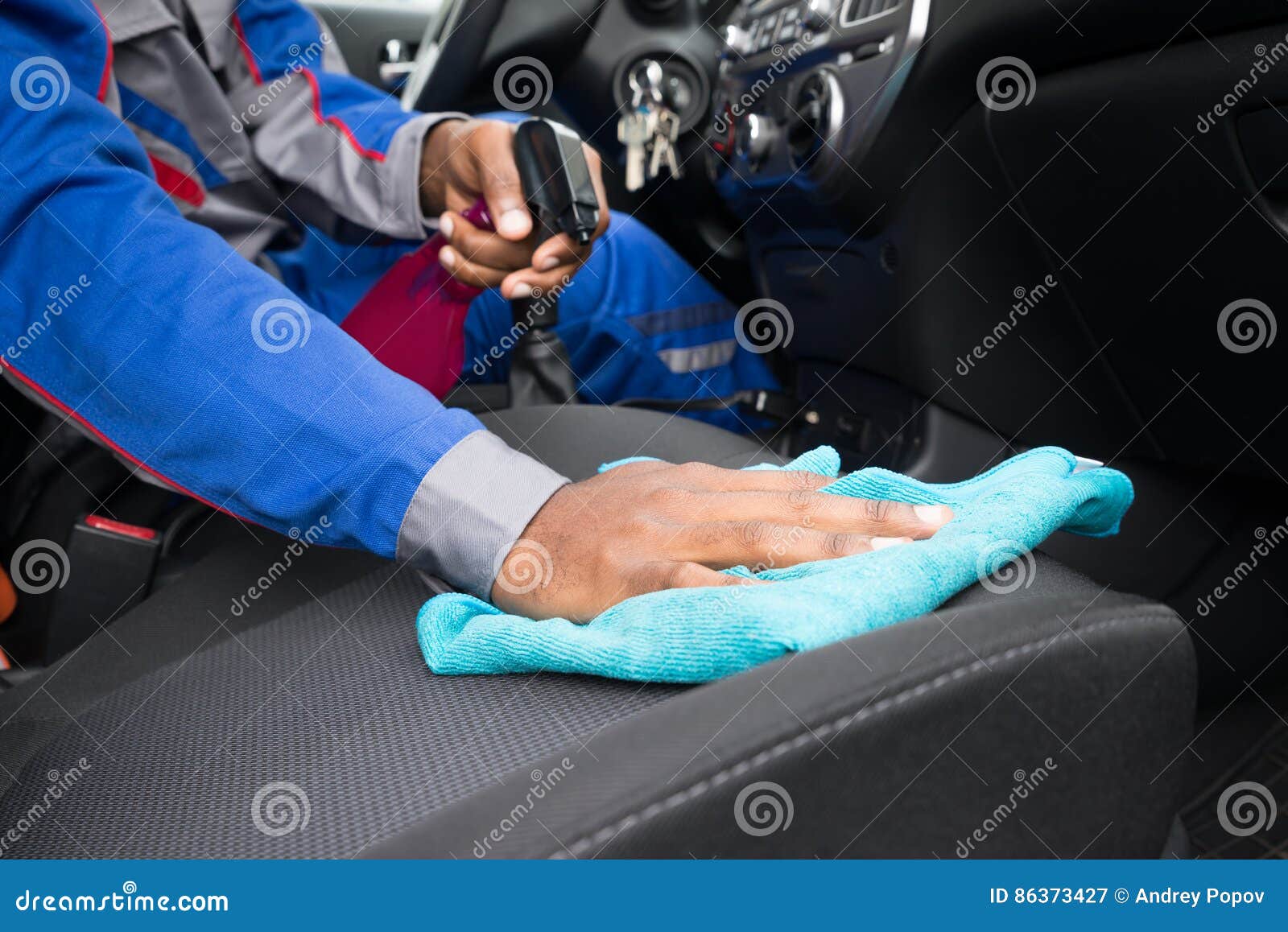 worker cleaning seat inside the car