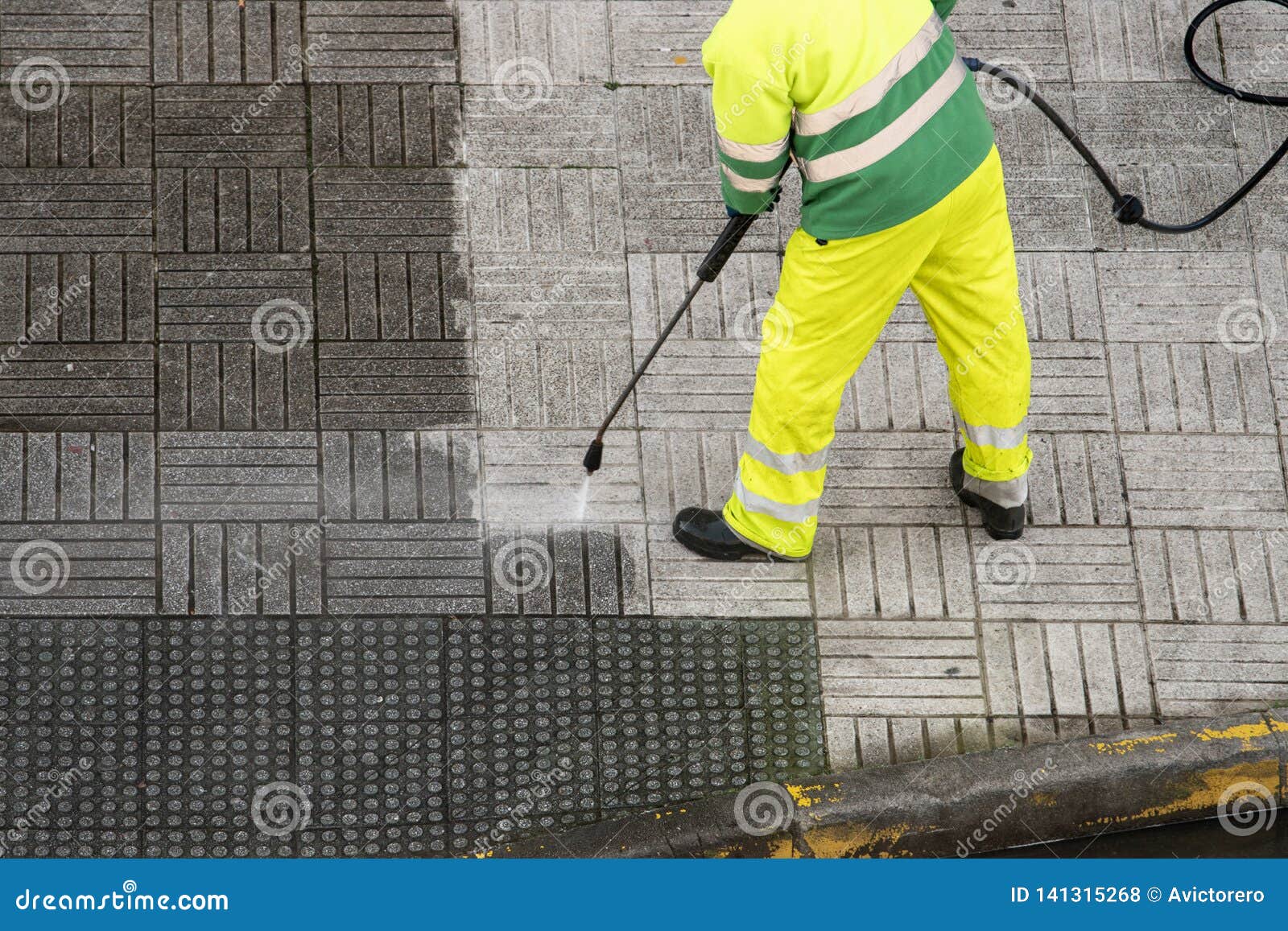 worker cleaning the street sidewalk with high pressure water jet
