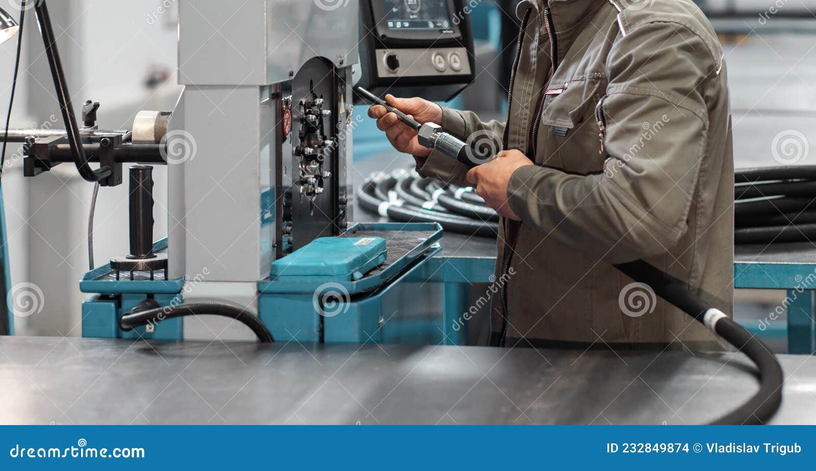 A Worker Crimps a High Pressure Hydraulic Hose on the Machine. Stock