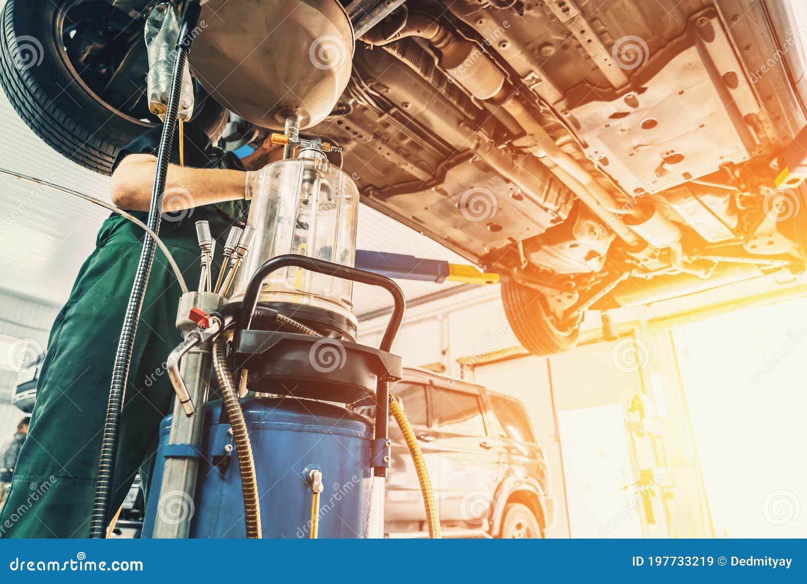 Worker Drains Oil from Engine Car during Service in Auto Service