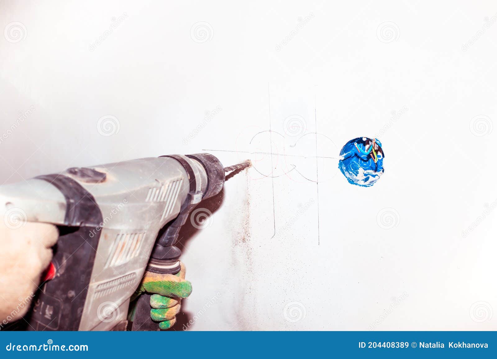 A Worker with a Drill Drills a Wall. Additional Electrical Outlet in