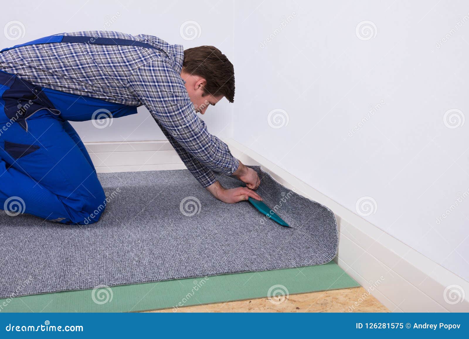 worker fitting carpet on floor
