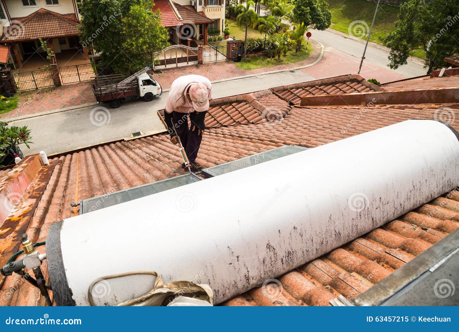 Worker Fixing Solar Water Heater on Roof during Maintenance Stock Image