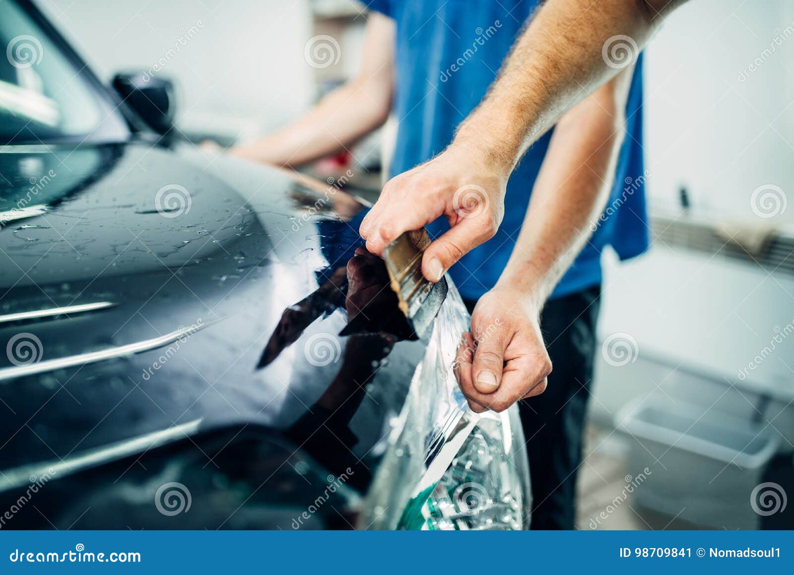 worker hands wraps car hood in protective coating