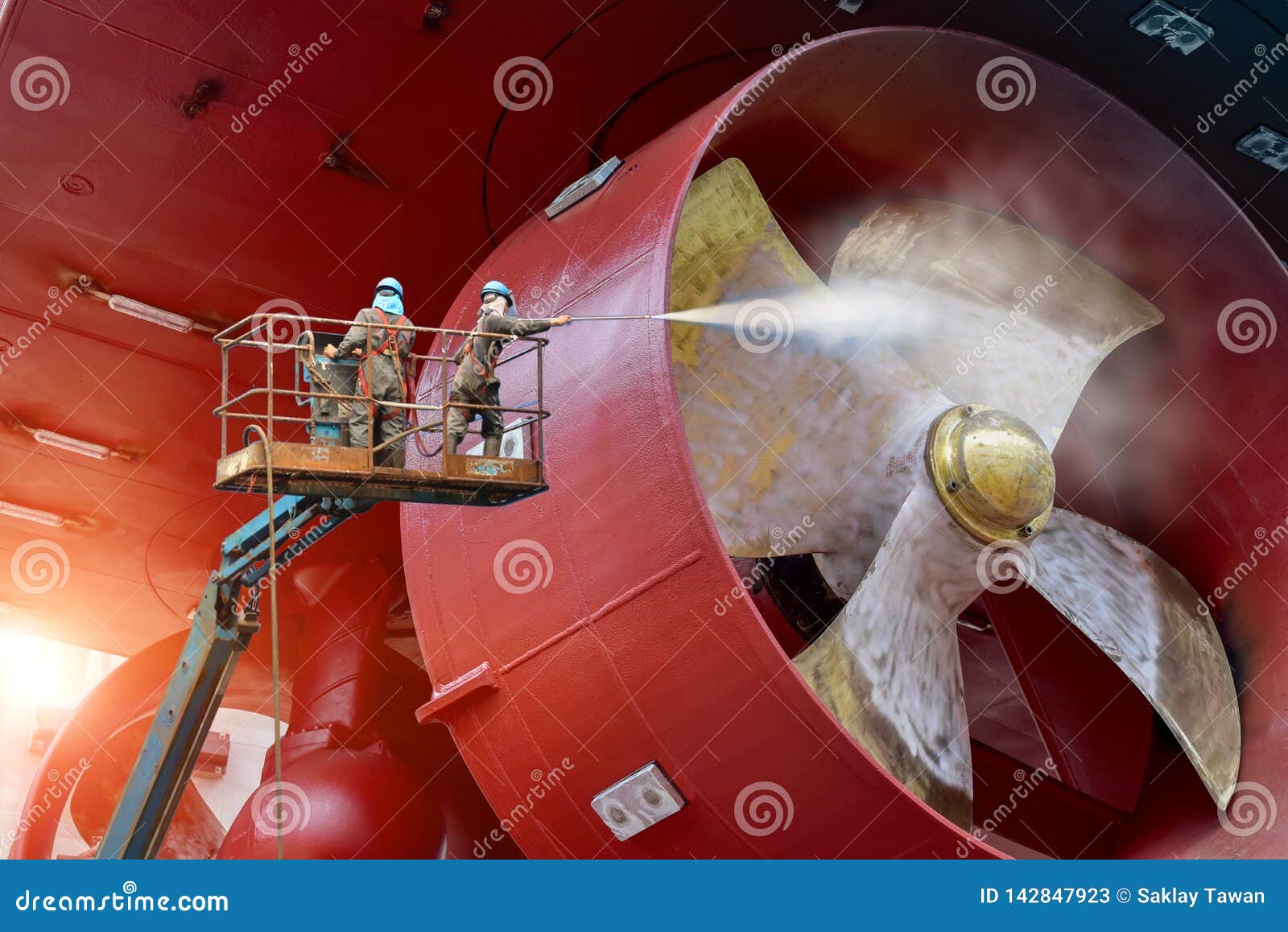 worker on high wear safety harness under washing propeller ship by jet water high pressure.