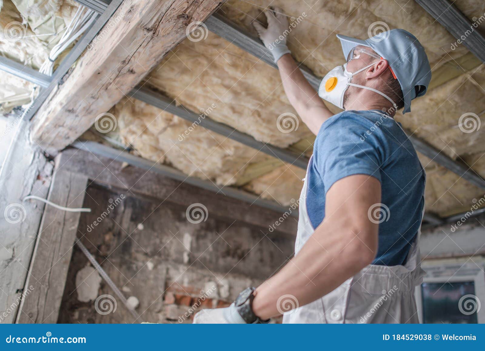 worker in his 30s replacing old attic mineral wool insulation