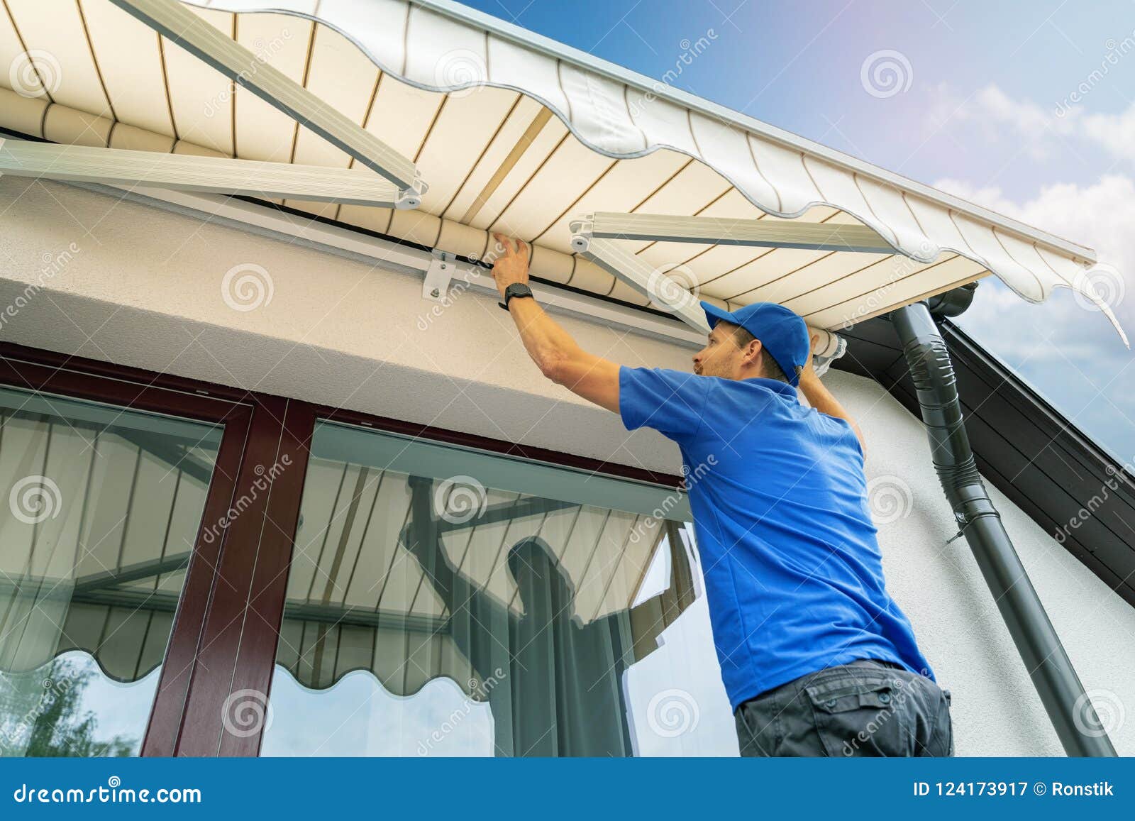 worker install an awning on the house wall over the terrace