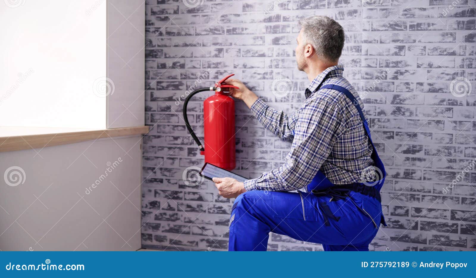 Worker Installing Fire Extinguisher. Inspection Service Stock Image