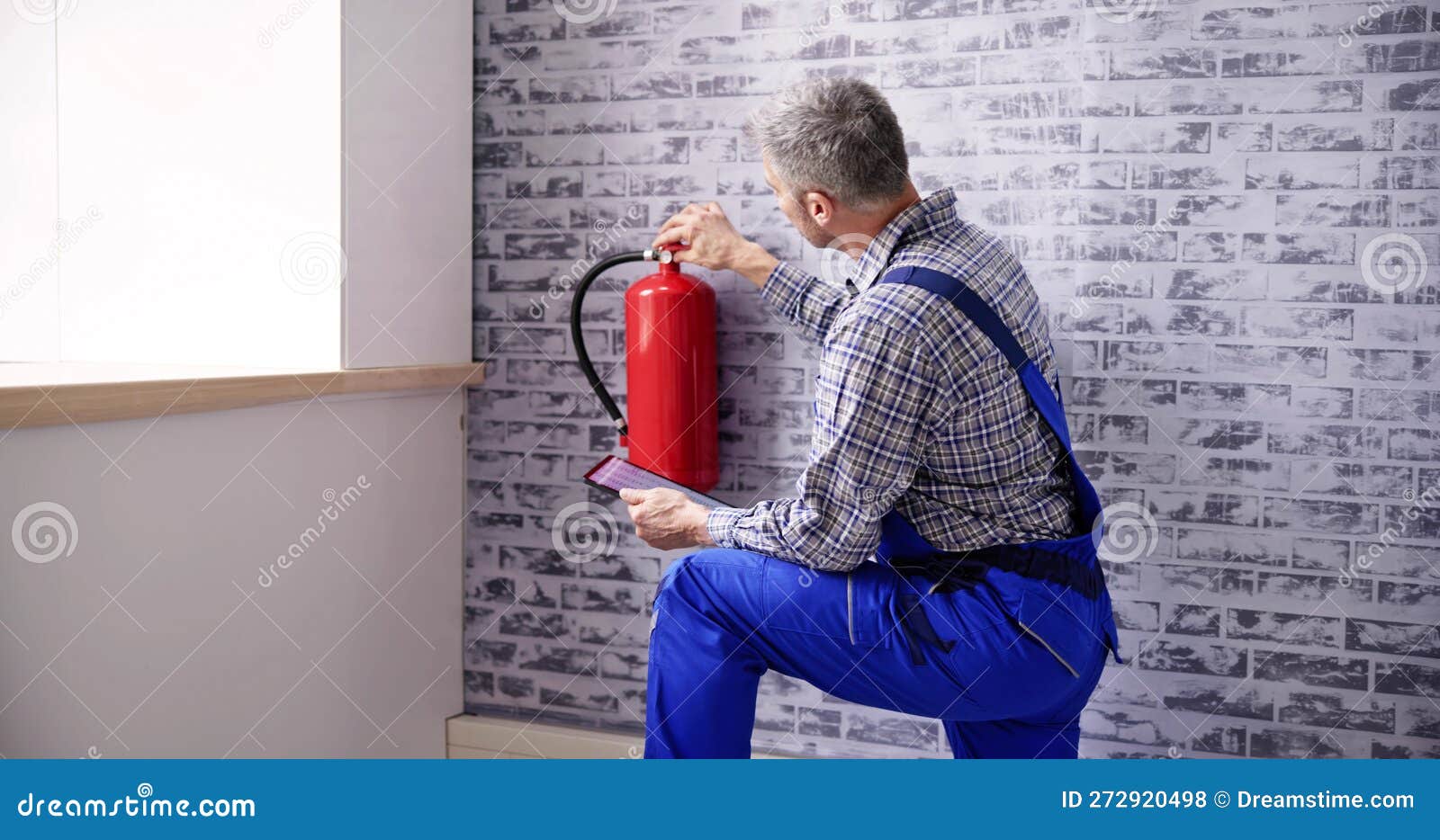 Worker Installing Fire Extinguisher. Inspection Service Stock Photo