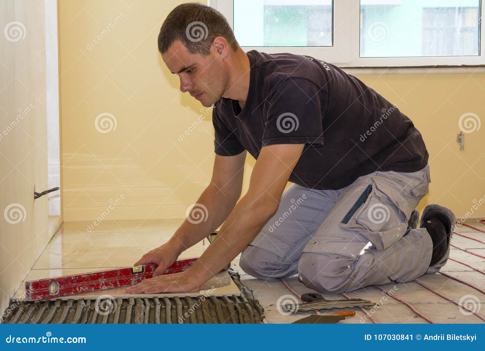 Worker Installing Floor Tiles. Ceramic Tiles and Tools for Tiler Stock