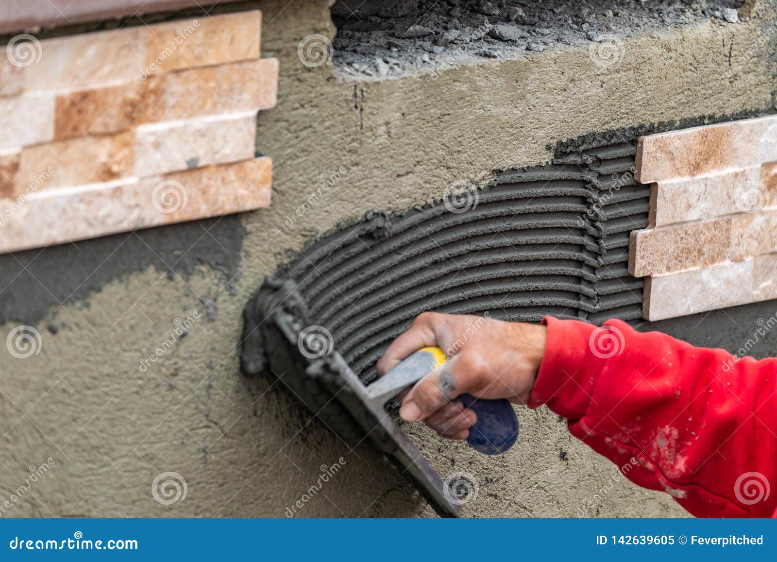 Worker Installing Wall Tile Cement with Trowel and Tile at Construction